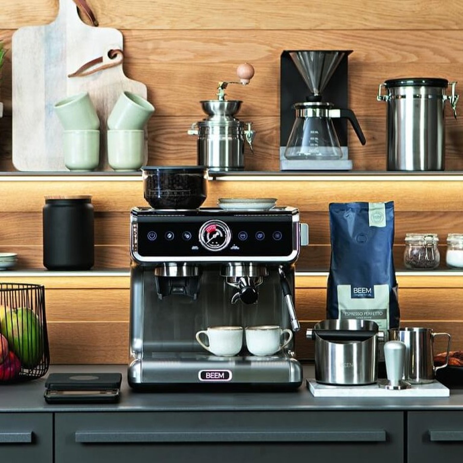 A hand uses a wooden-handled tamper on coffee grounds in a portafilter on a wooden countertop.