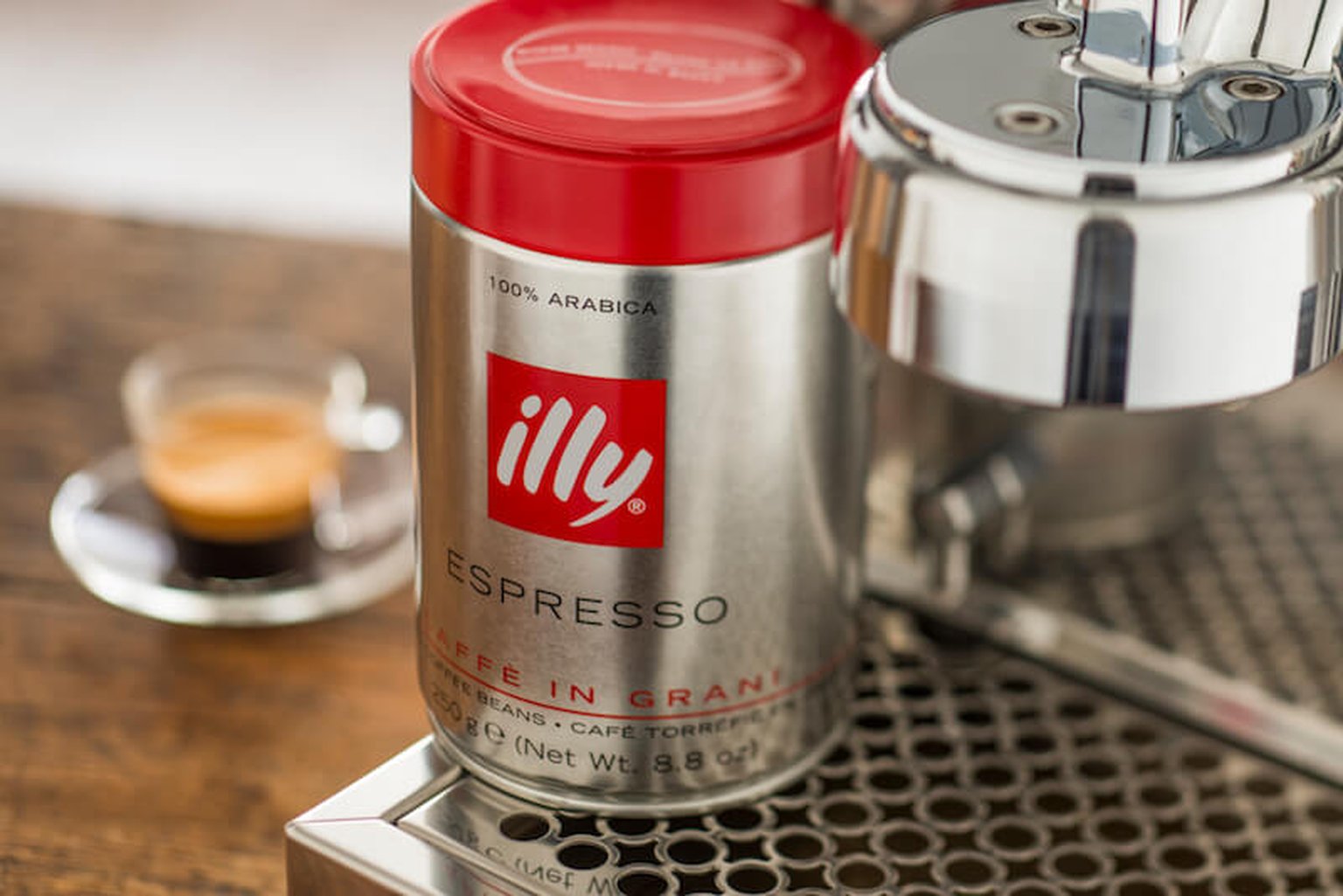 Illy coffee beans in a tin next to an espresso machine