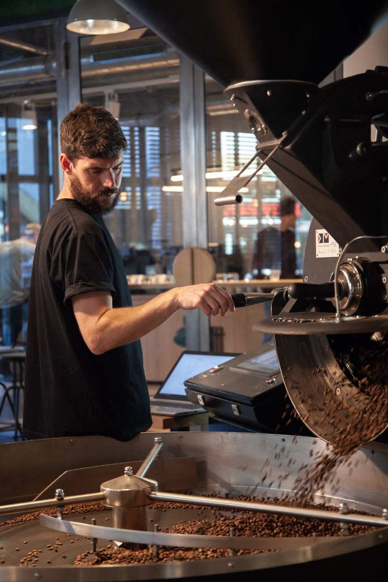 a man at a coffee roastery machine roasting coffee