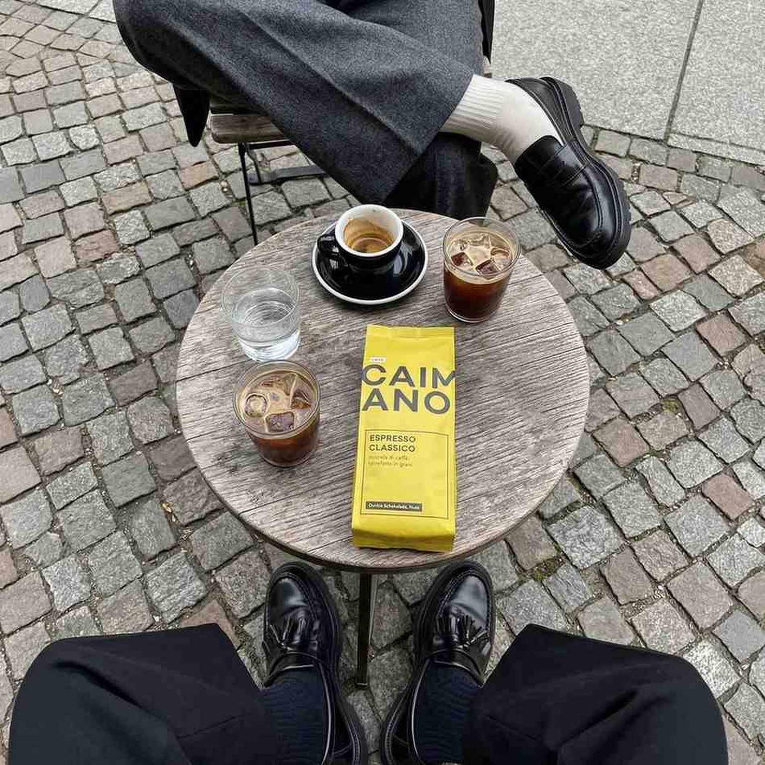 caimano on a wooden table with espressso and iced americano