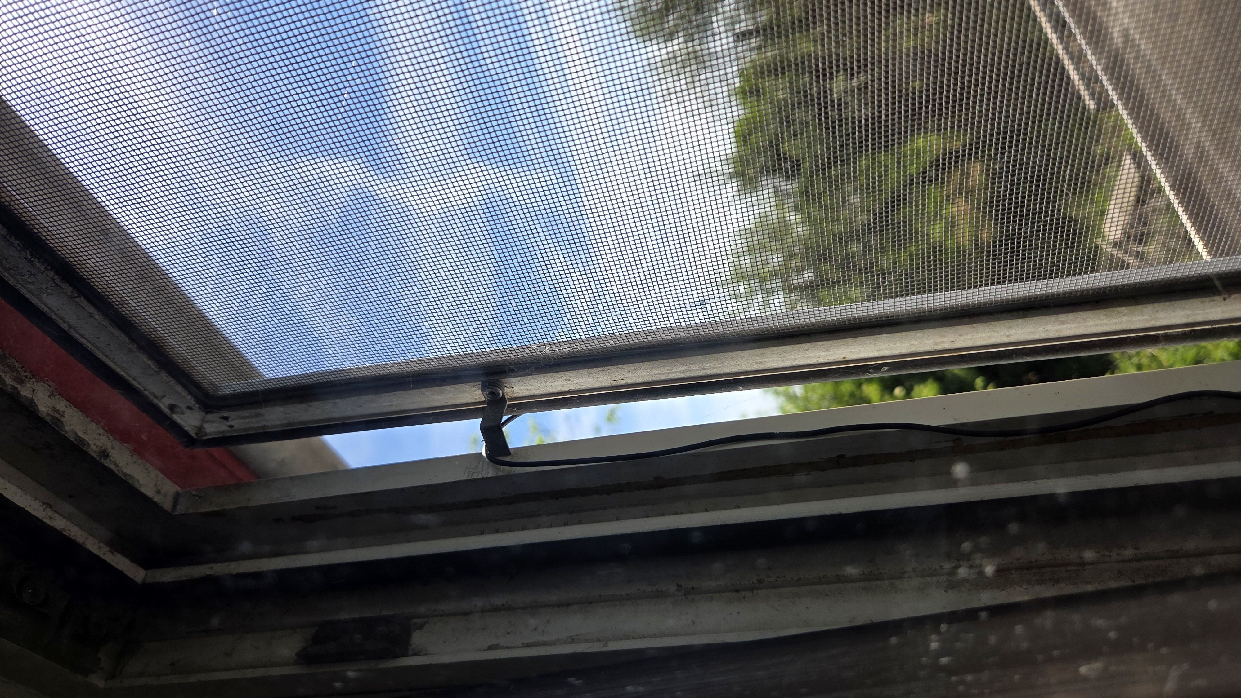 A small USB microphone hanging outside a window