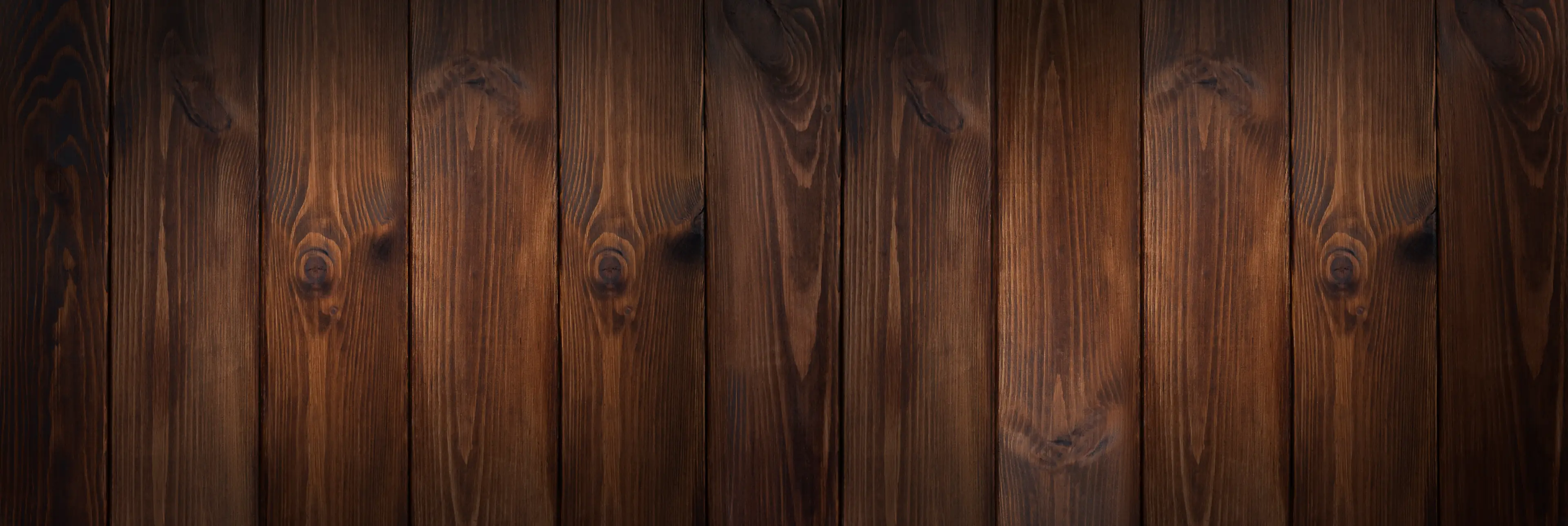Dunkle Holzplanken mit einer markanten Maserung und warmen Farbtönen, die nahtlos vertikal verlegt sind.