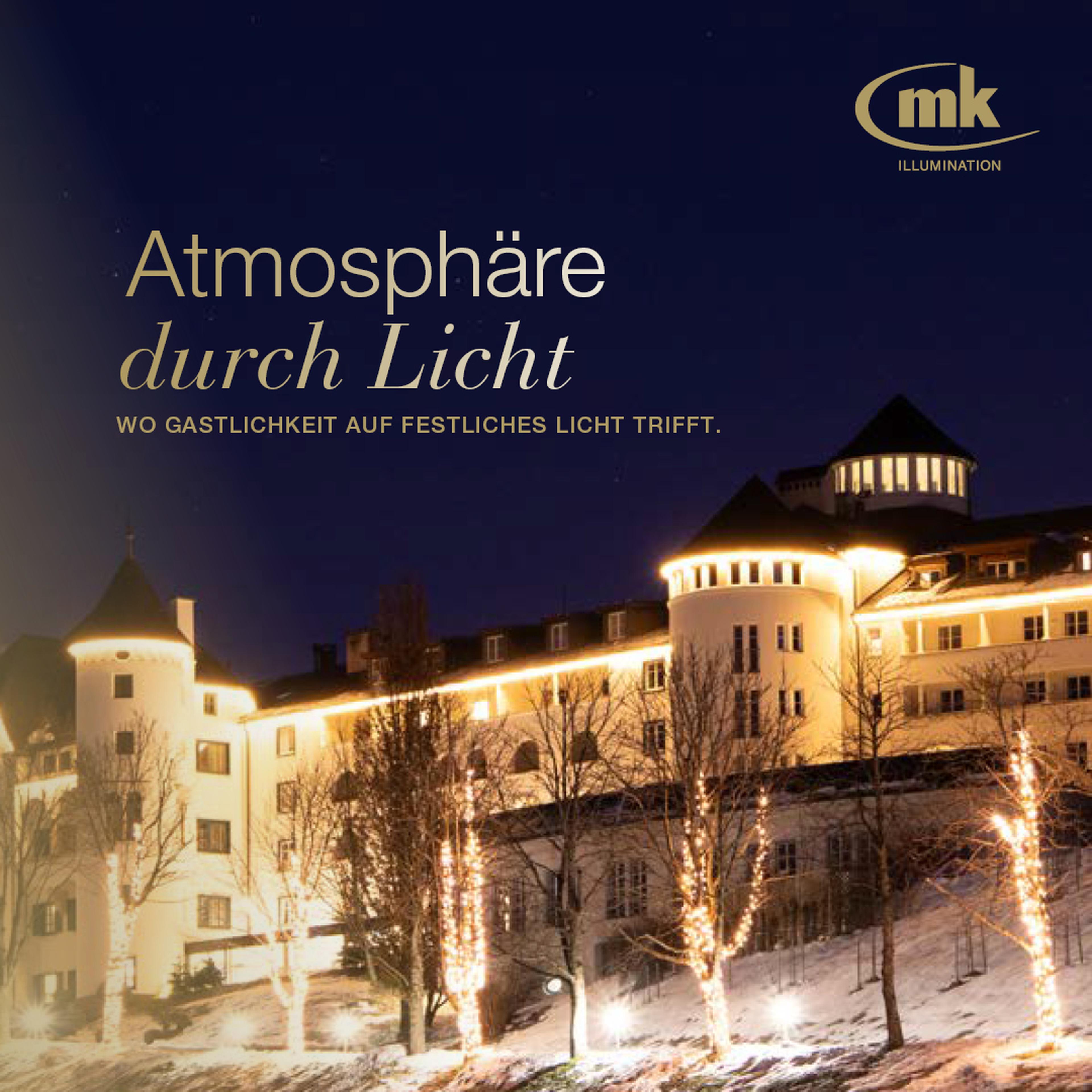 Beleuchtetes Gebäude bei Nacht, umgeben von winterlicher Atmosphäre. Text: "Atmosphäre durch Licht" und "mk Illumination".