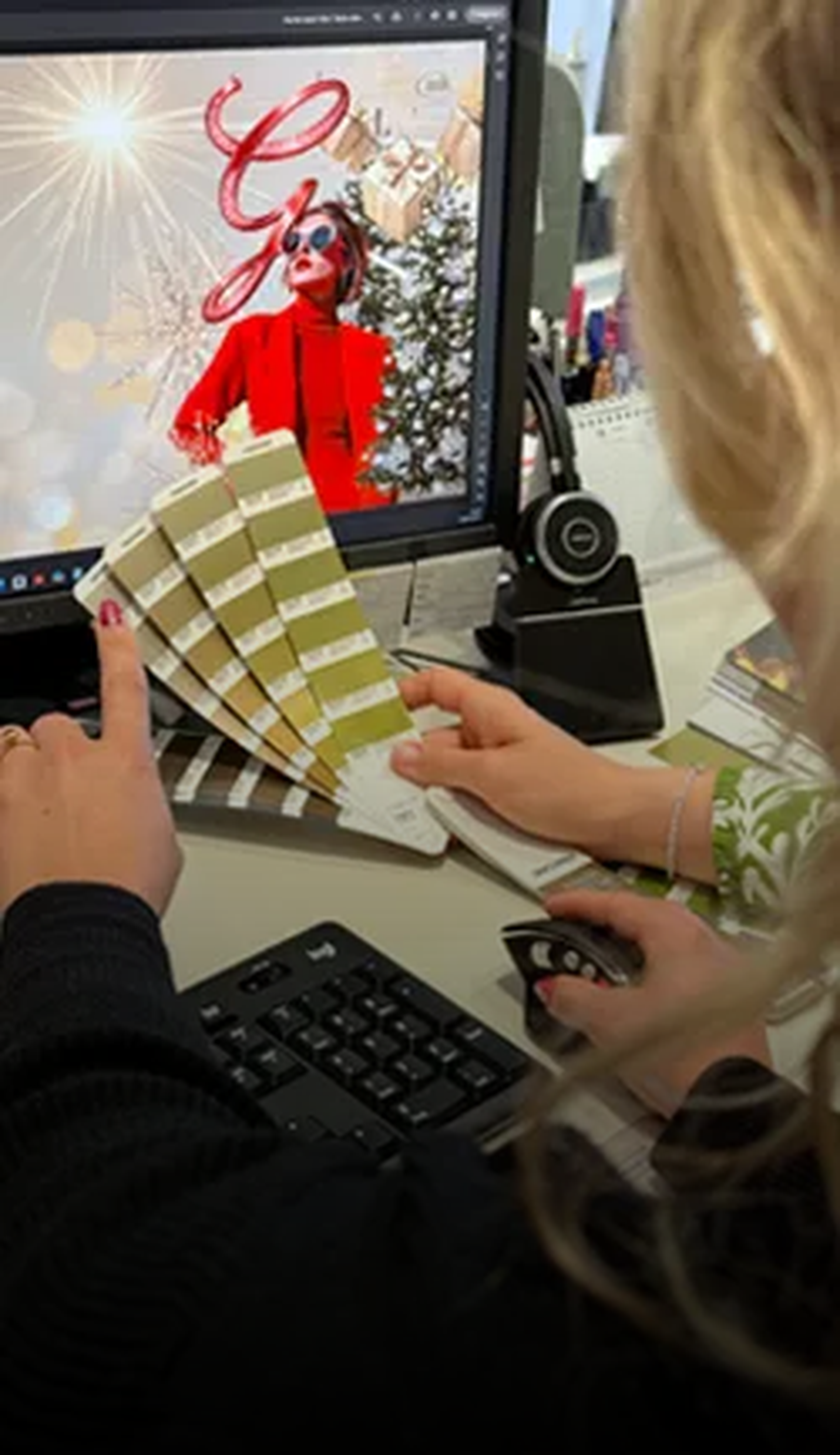 Personen wählen Farbtöne mit einem Farbdiagramm vor einem Computerbildschirm mit festlicher Grafik.