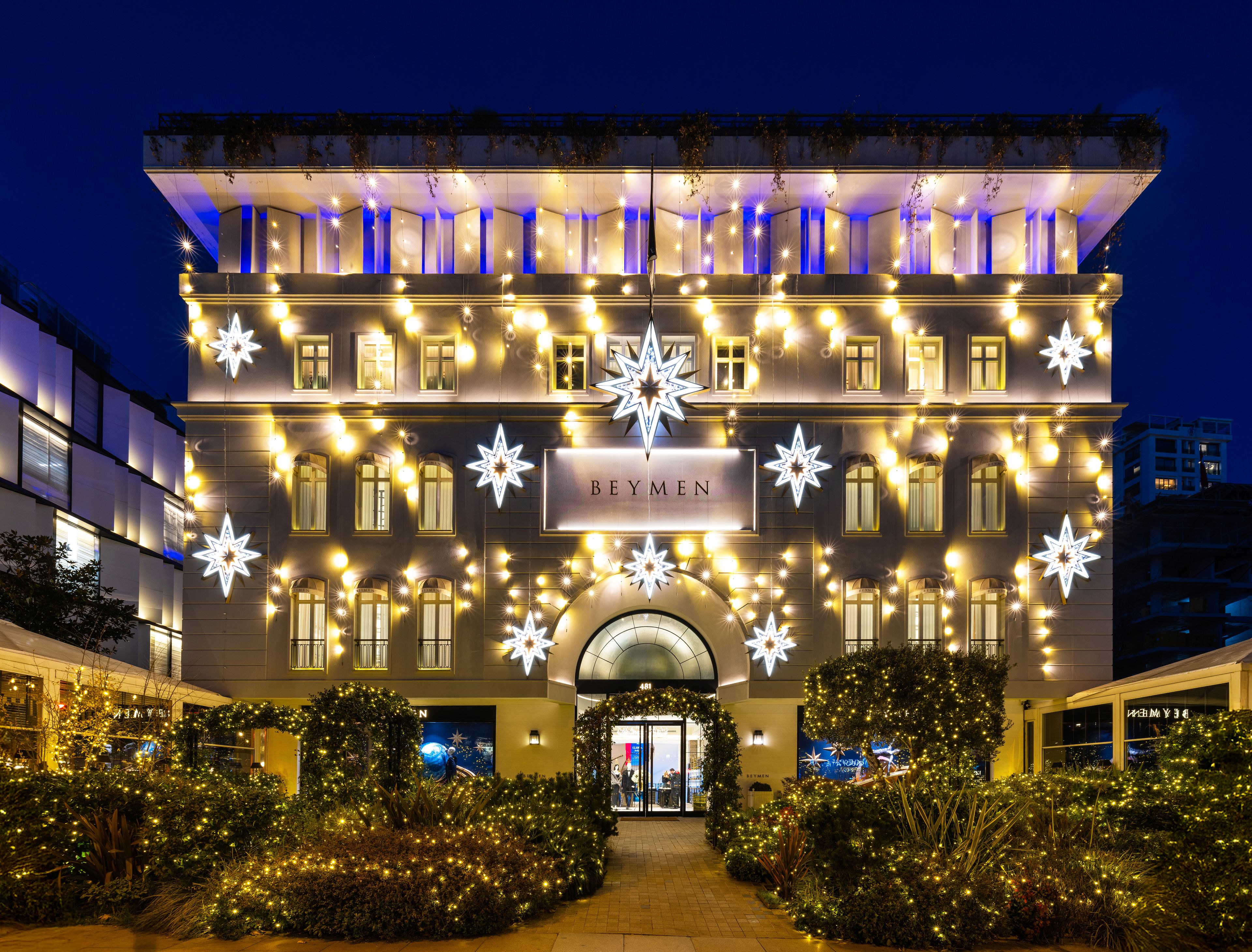 Festlich beleuchtete Fassade eines Gebäudes, dekoriert mit strahlenden Sternen und Lichtergirlanden in der Nacht.