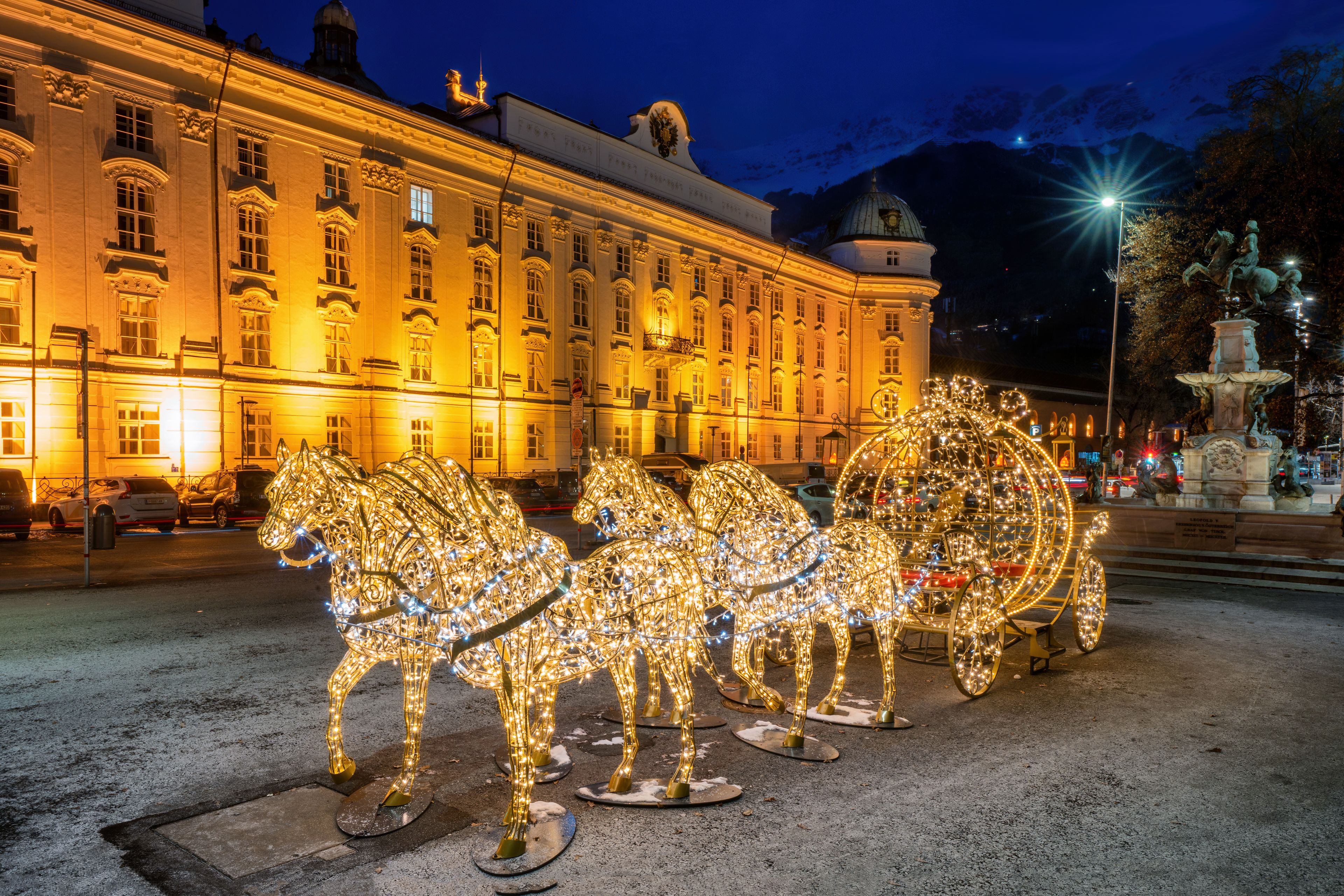 Illuminierte Pferde-Dekorationen vor einem hell erleuchteten historischen Gebäude bei Nacht, festliche Beleuchtung.