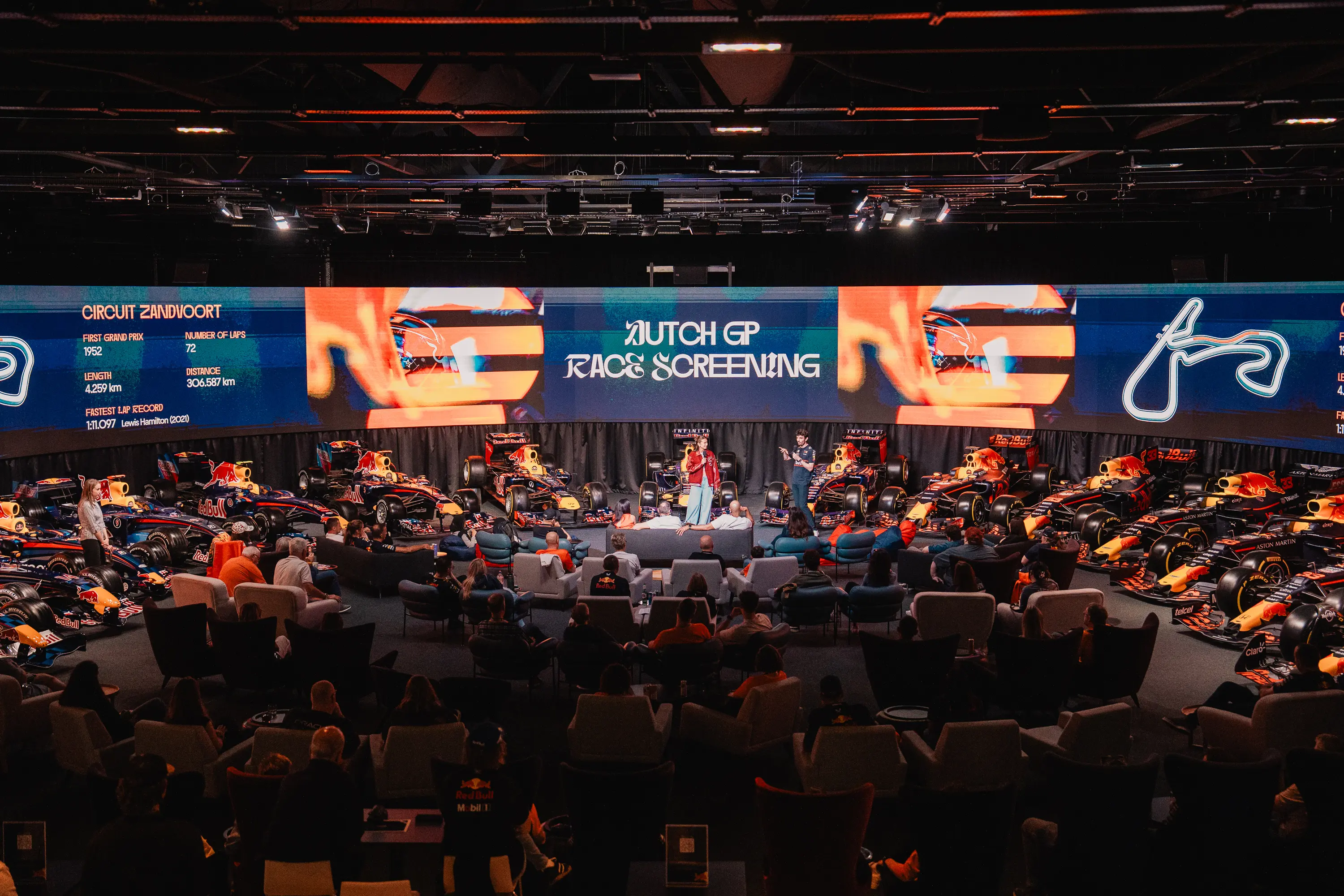 MK7 event space hosting a Dutch GP race screening with Oracle Red Bull Racing F1 cars displayed and an audience seated in front of a big screen.