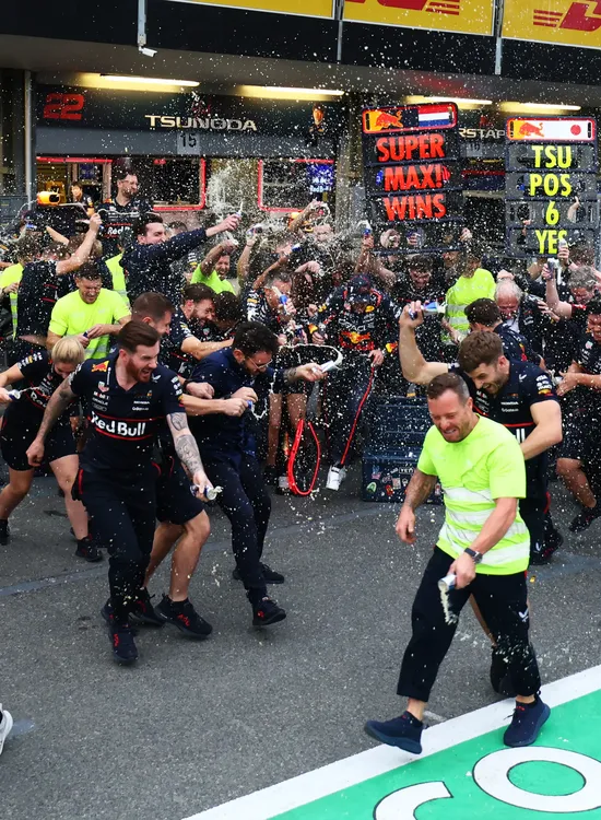 Oracle Red Bull Racing team celebrates grandly in the pit lane, spraying drinks and cheering after a significant win at the race.