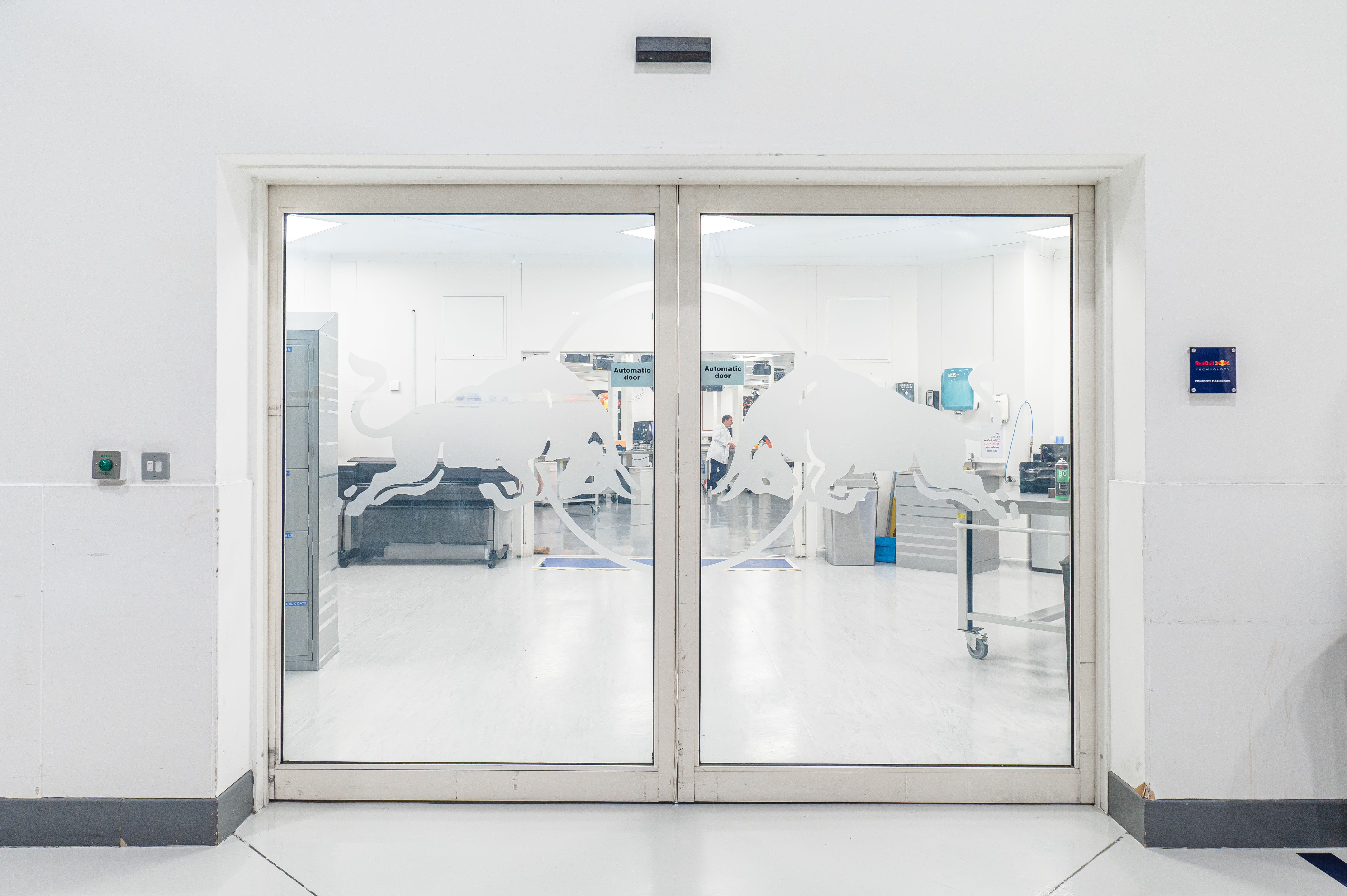 Frosted glass doors with a bull logo open to a clean, modern office space with white walls and equipment visible inside.