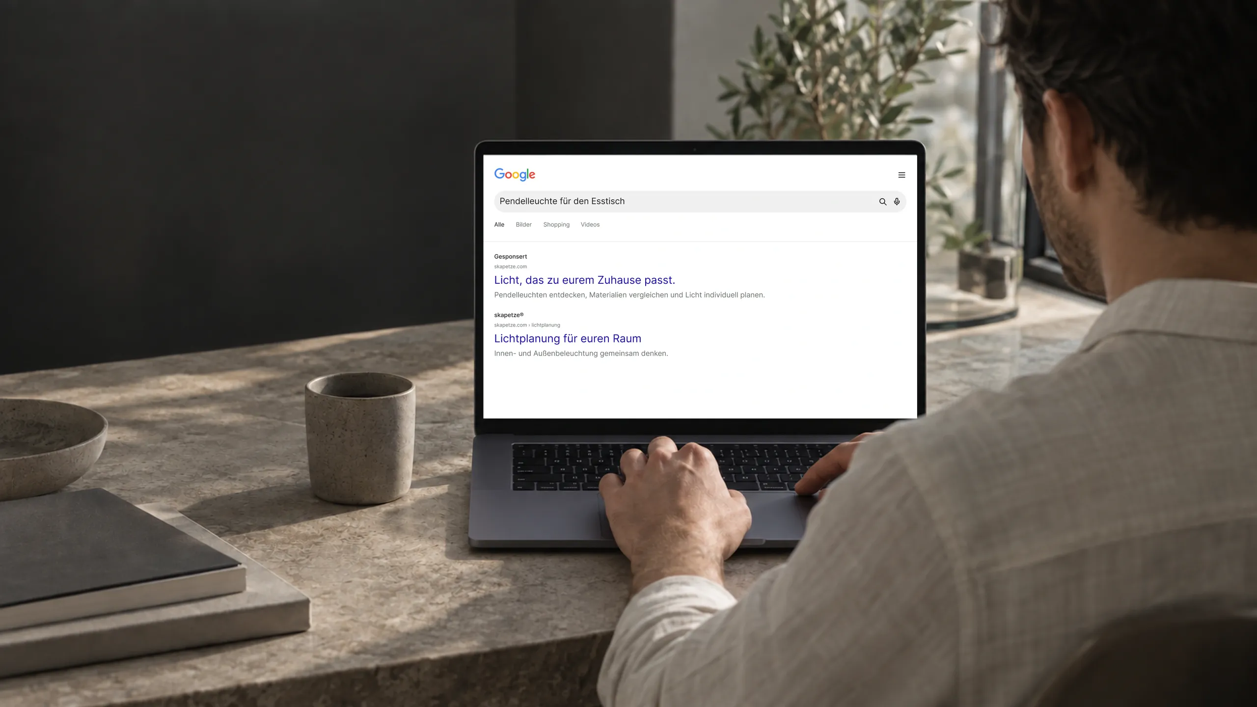Person am Laptop mit einer Google-Suche und einer Leuchtenanzeige.