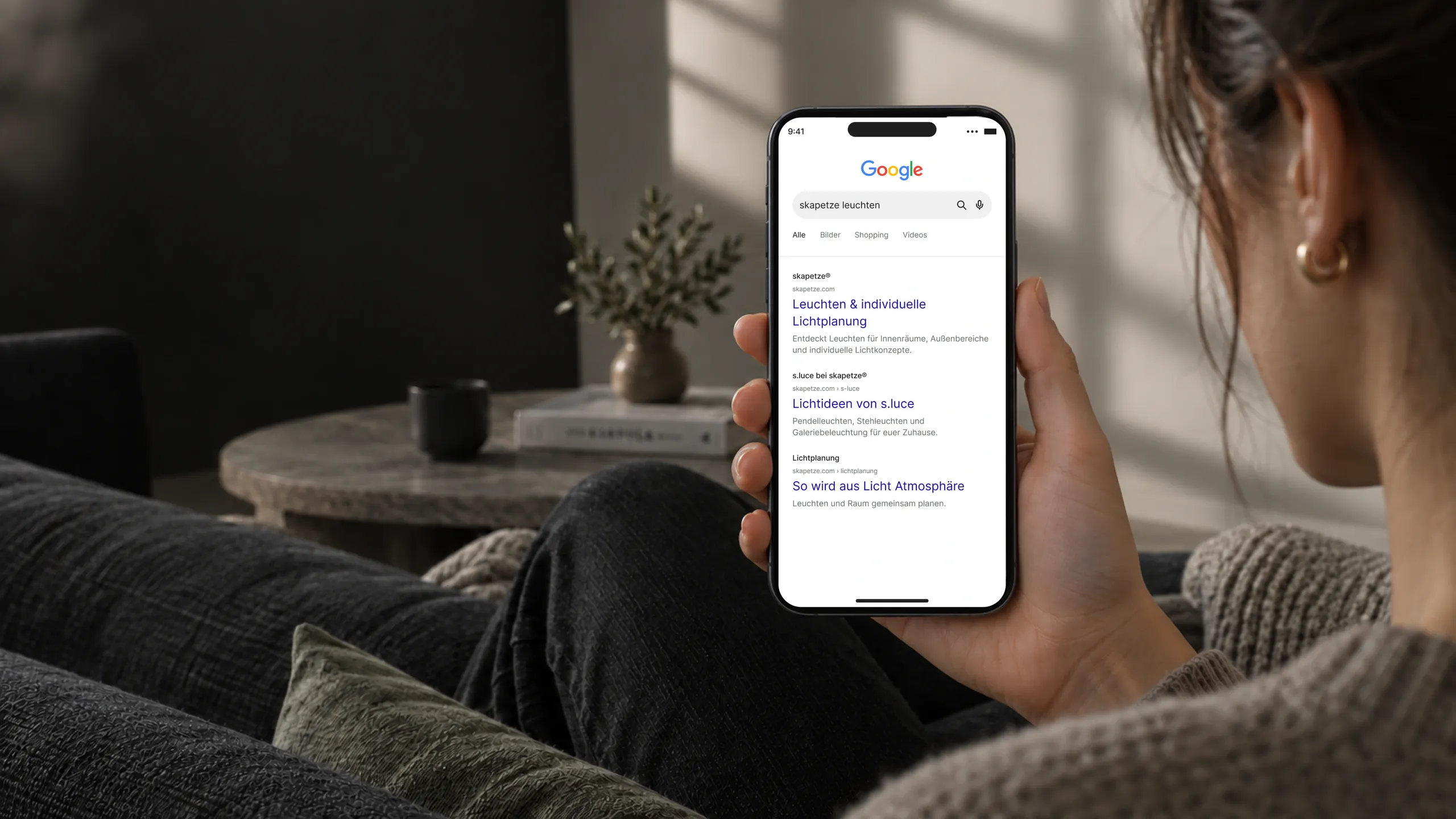 Person mit Smartphone und Google-Suchergebnissen zu skapetze-Leuchten.