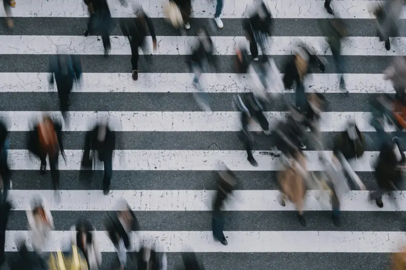 Commuters crossing a zebra crossing, seen from above, motion blurred