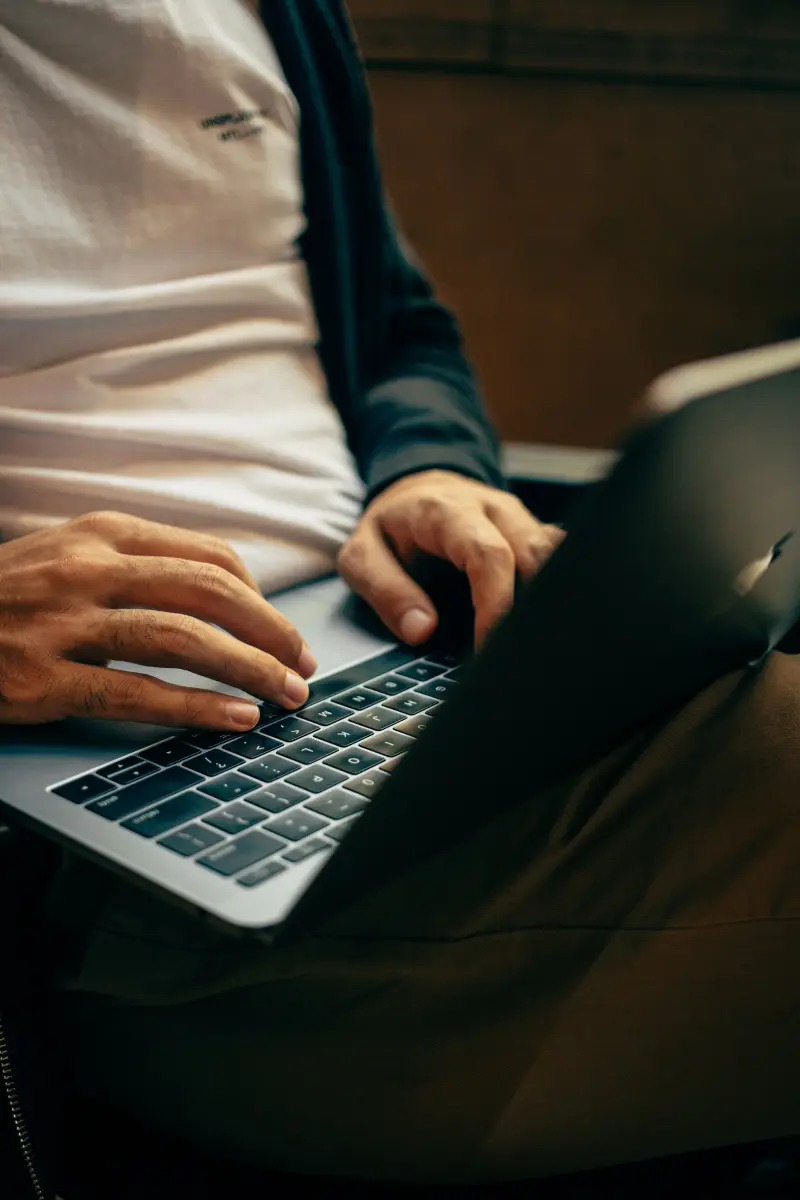 Close view of hands typing on a laptop keyboard in low warm light