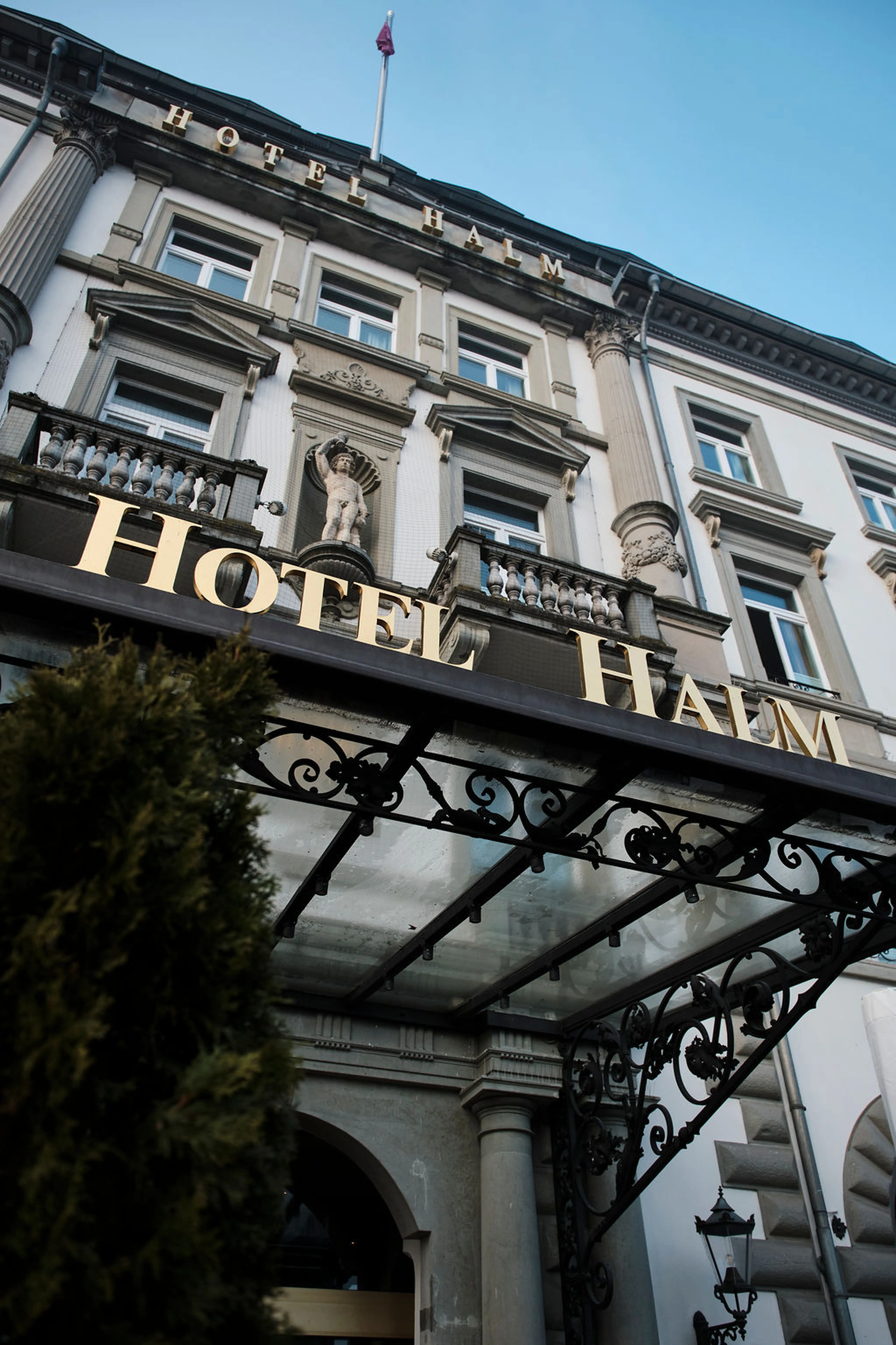 Fassade des Hotel Halm mit dekorativer Verglasung und künstlerischen Verzierungen, darüber der Schriftzug "Hotel Halm".