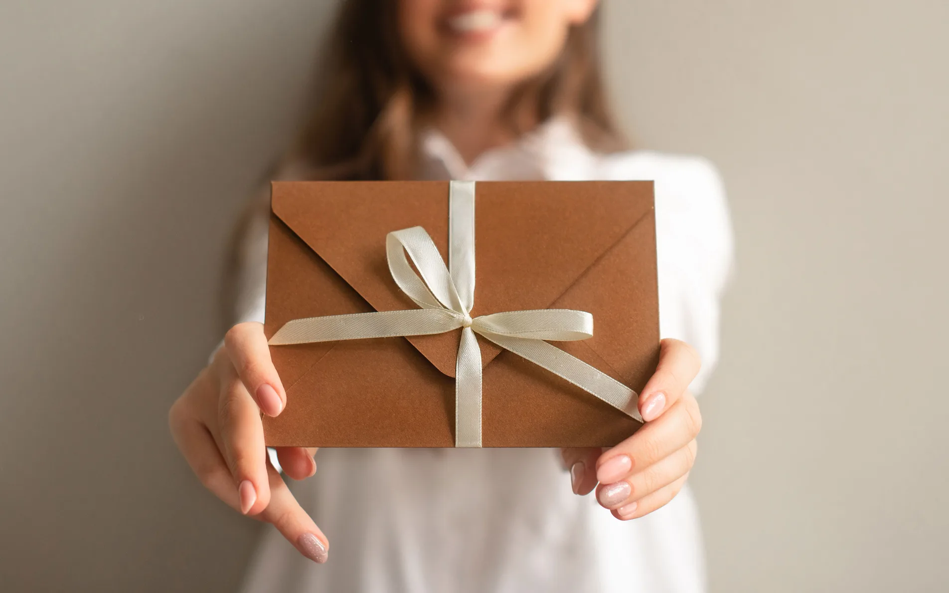 Geschenkgutschein mit Satinband wird in die Kamera gehalten