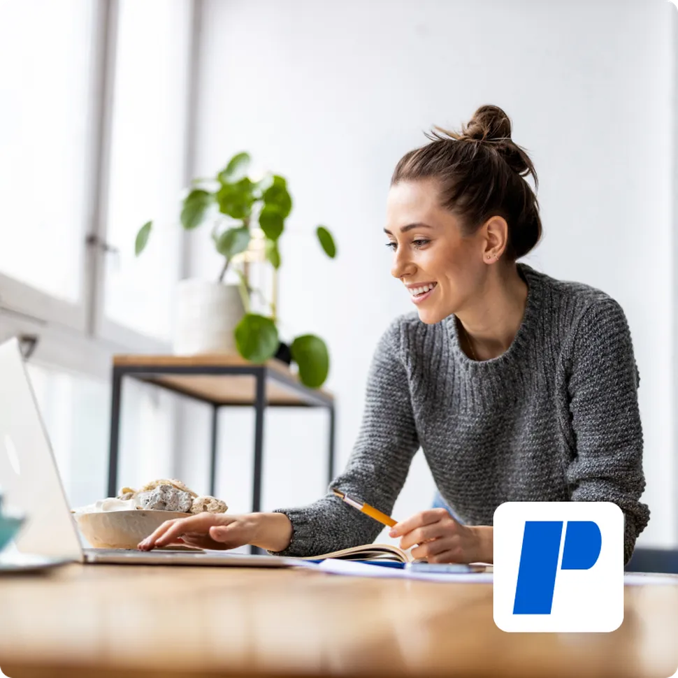 A woman working on her computer doing market research with a pland in the backgroung
