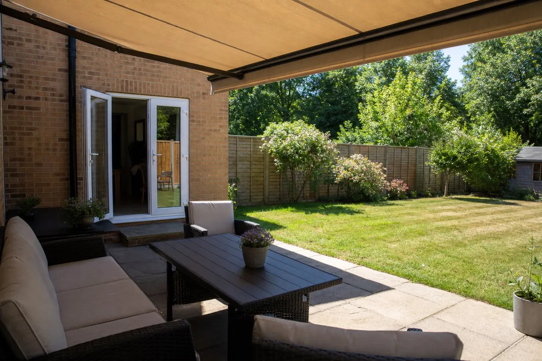 A retractable awning shading a patio and patio doors from the sun