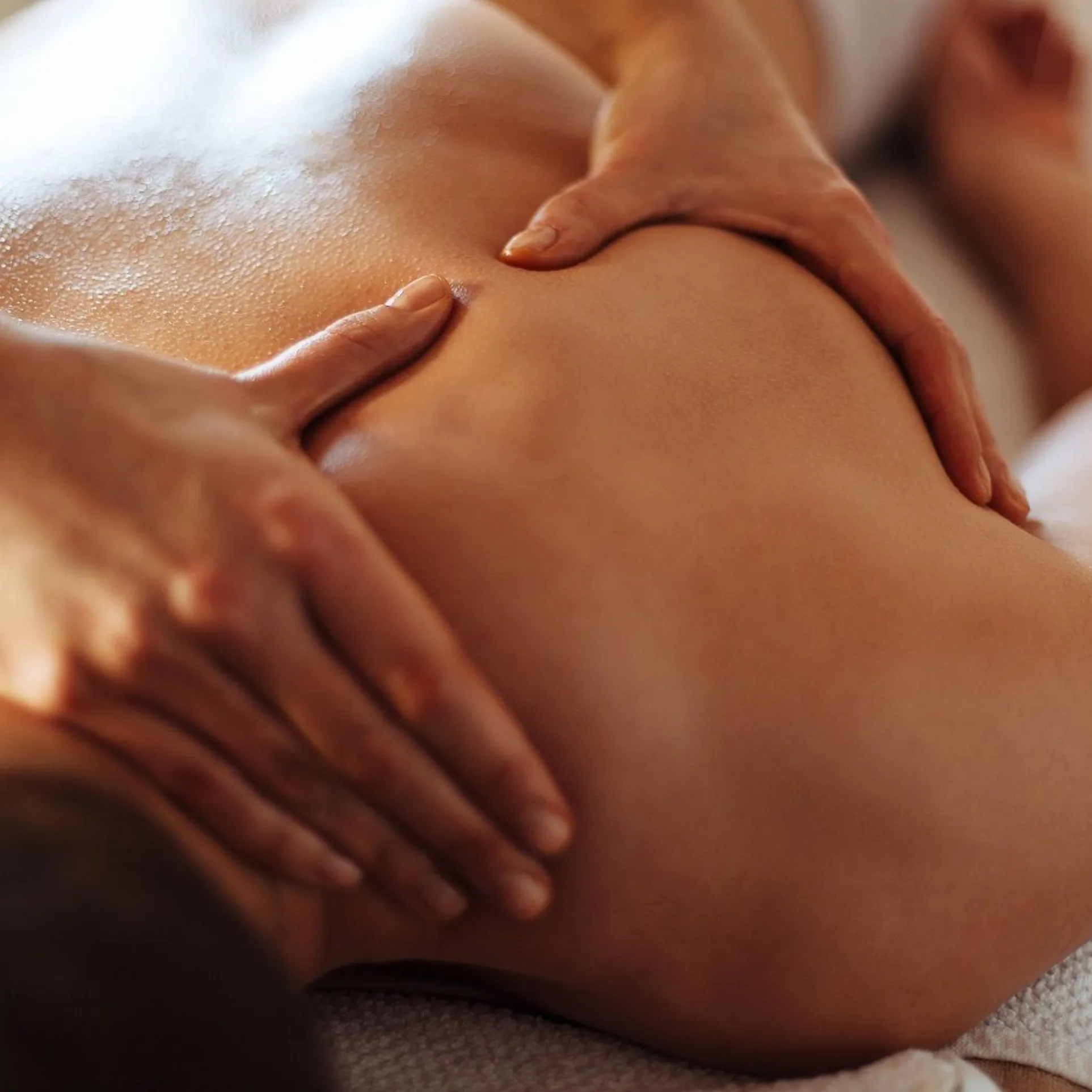 Therapist applying firm pressure during a deep tissue back massage at an at-home treatment
