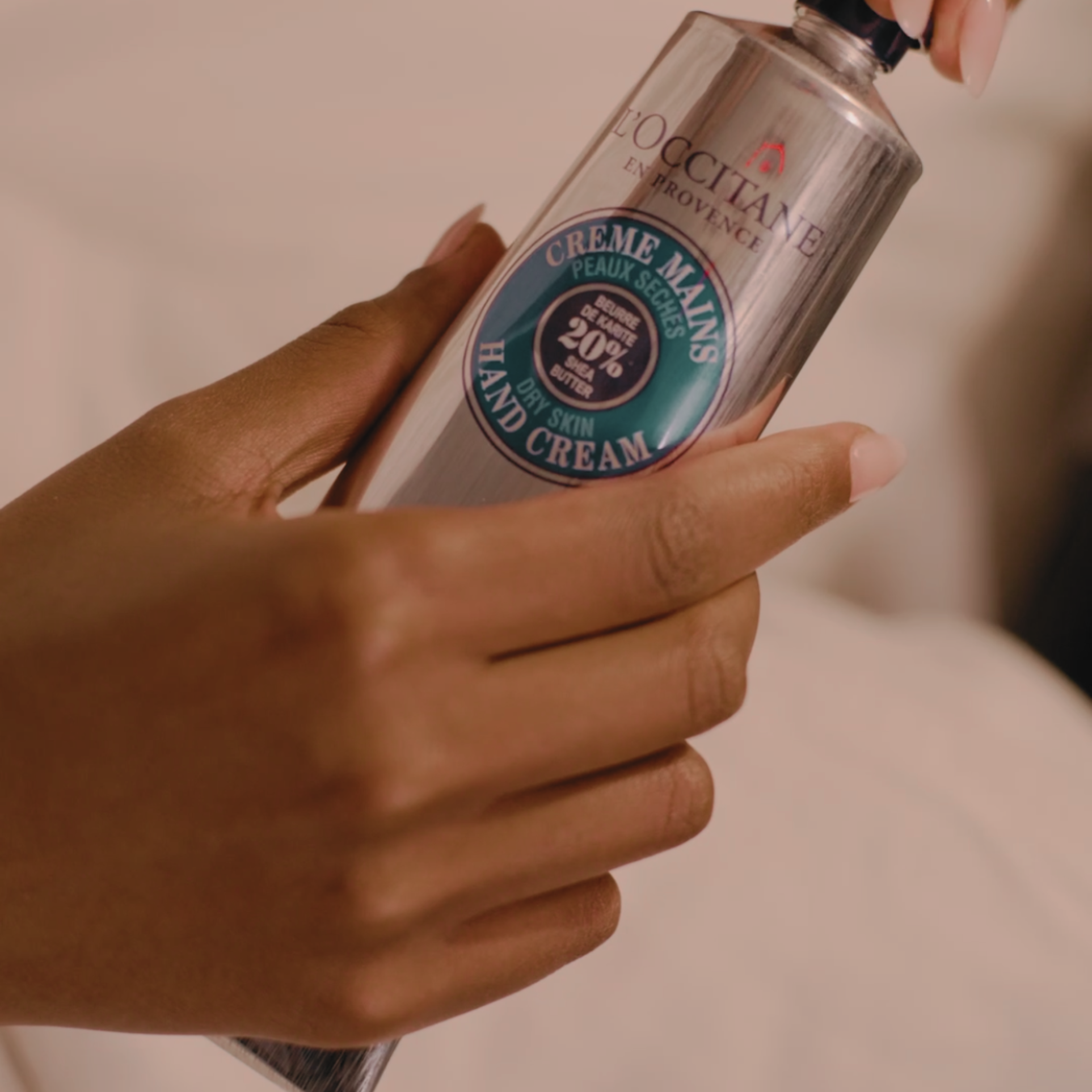 Hands applying L'Occitane shea butter hand cream during a manicure treatment.