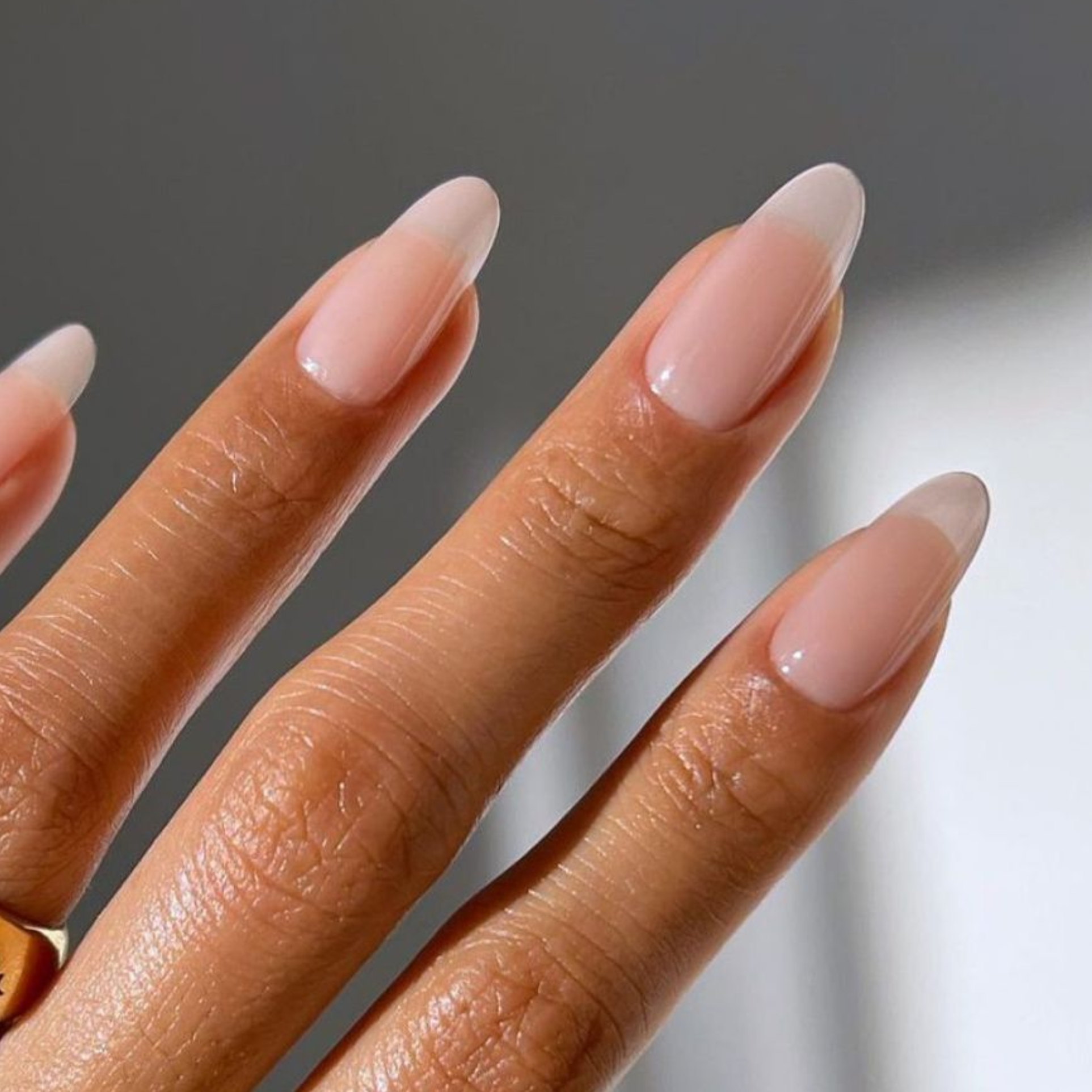 Close-up of long almond-shaped nails with a sheer, natural finish after a Russian manicure