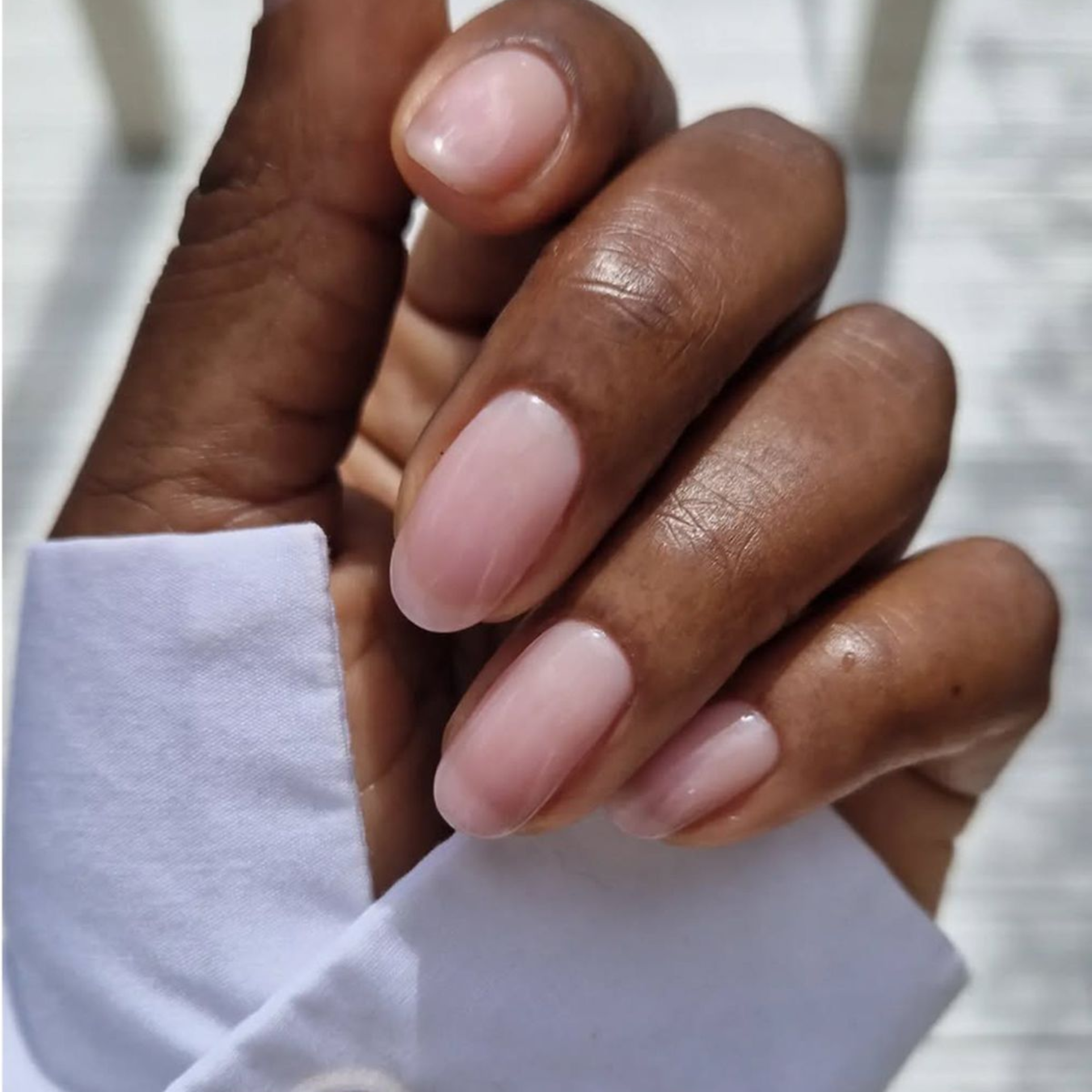 Close-up of long almond-shaped nails in a nude builder gel manicure