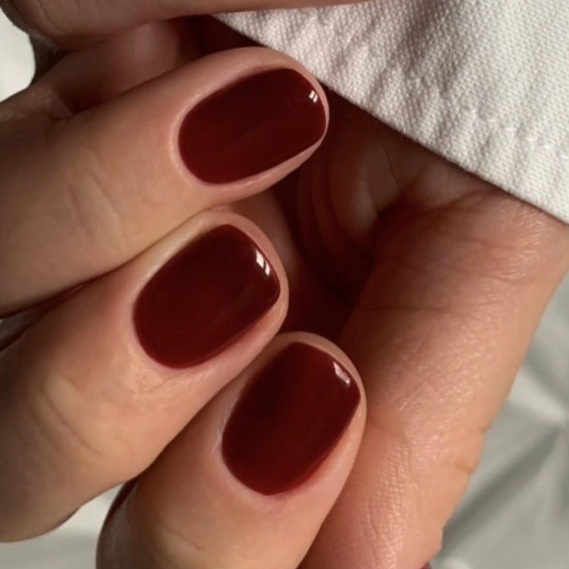 Close-up of short nails in a glossy deep red gel manicure