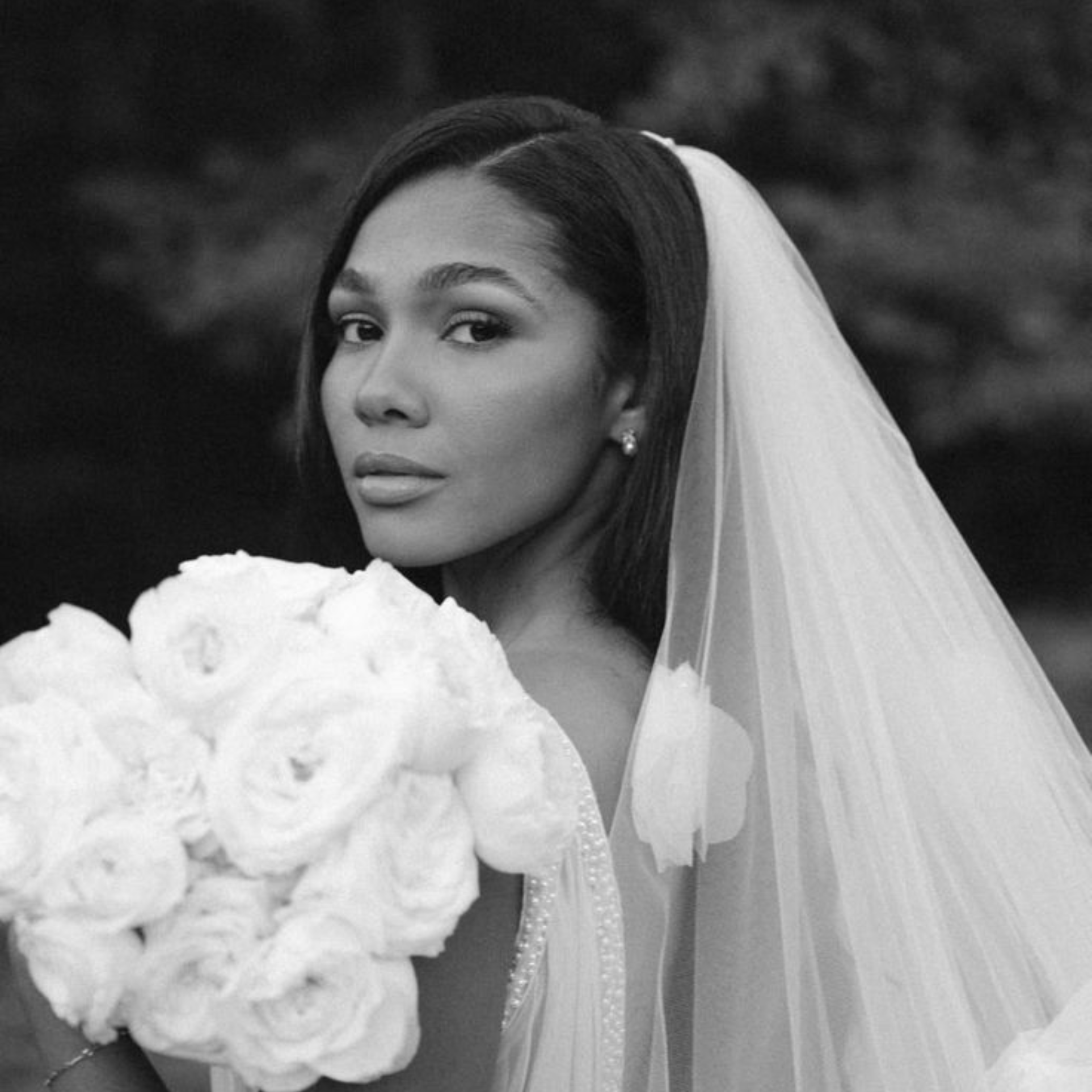Bride with sleek hair, veil and natural bridal makeup holding a white rose bouquet