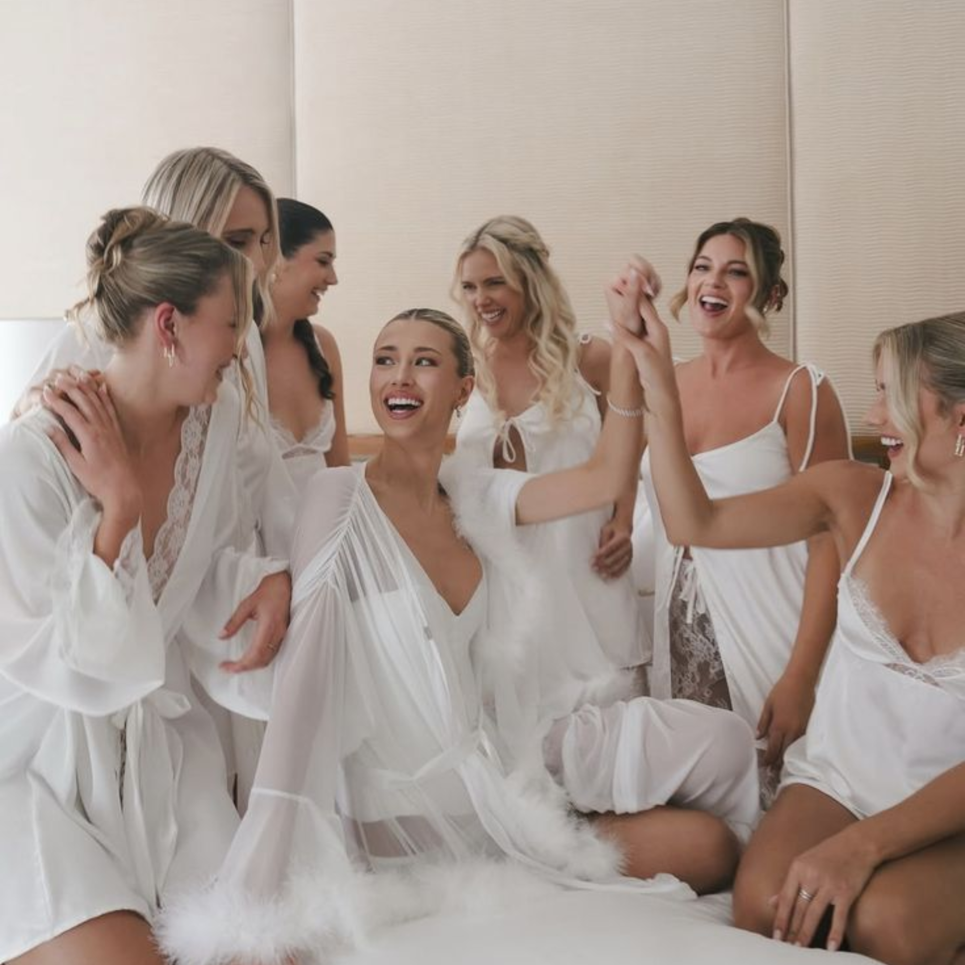 Bride and bridal party in white robes with bridal hair and makeup, getting ready together