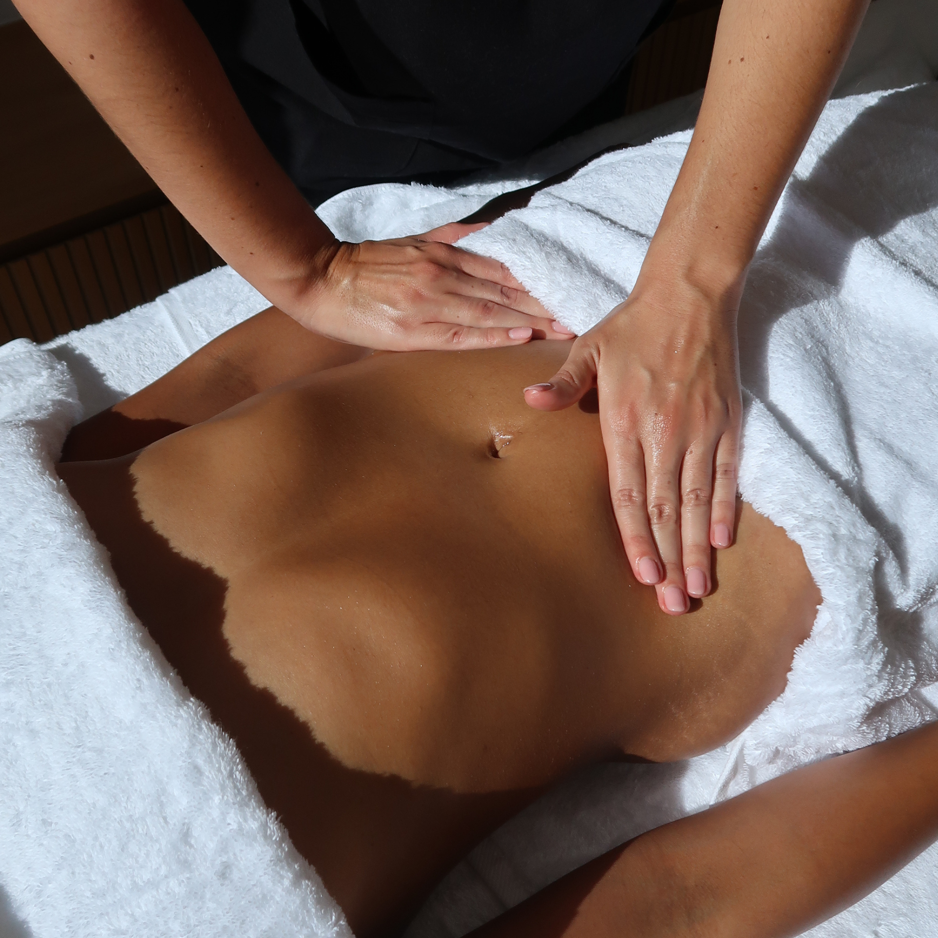 Therapist performing a lymphatic drainage massage on the abdomen during an at-home treatment