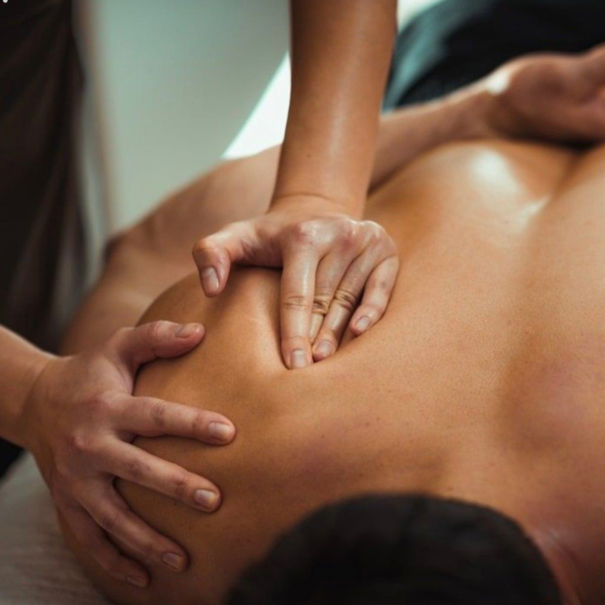 Therapist working into the shoulder muscles during a sports massage at an at-home treatment