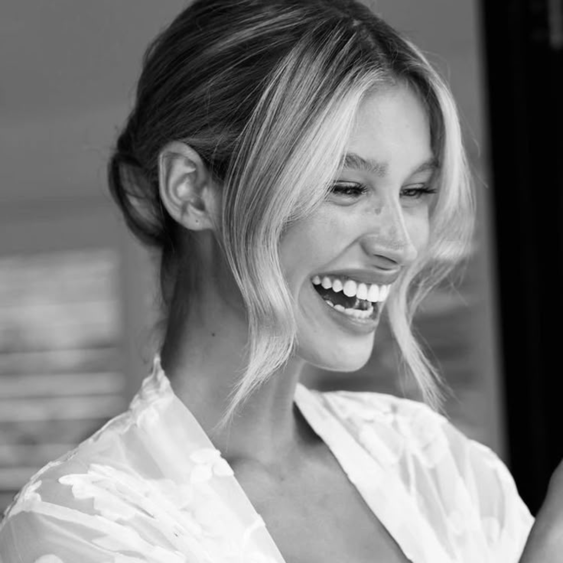 Smiling bride with a soft updo and face-framing pieces, getting ready on her wedding day