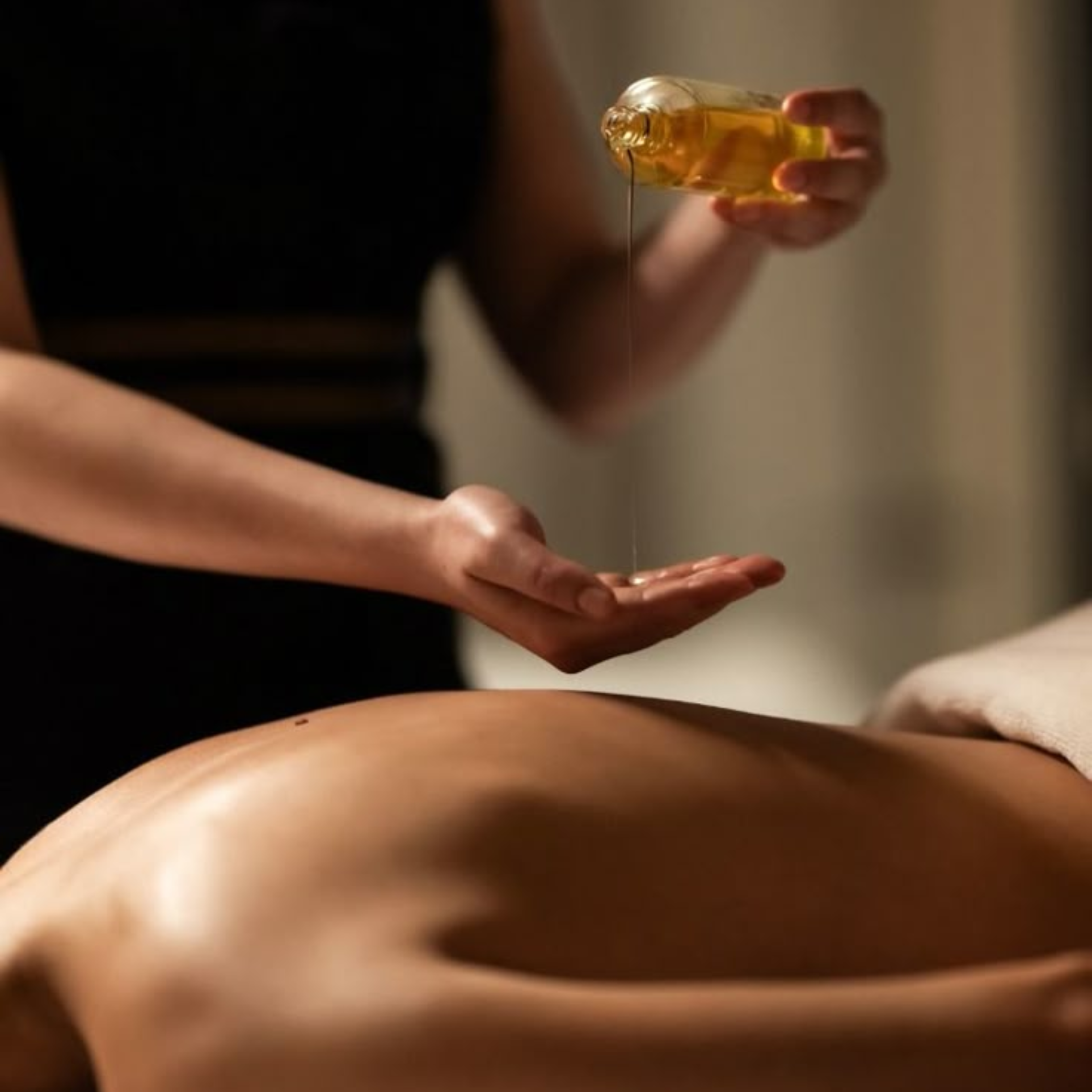 Therapist pouring aromatherapy oil before a massage during an at-home treatment