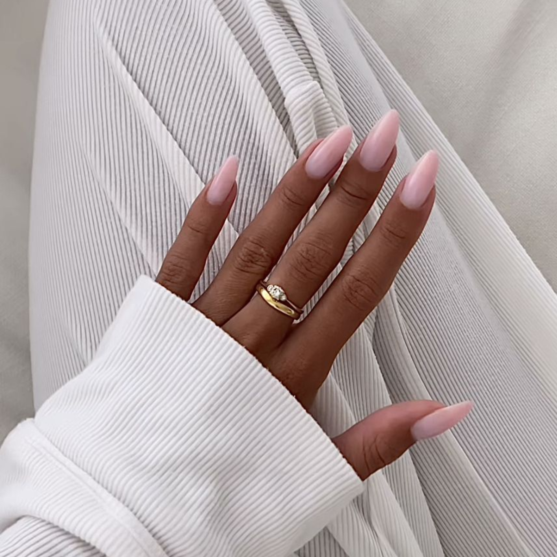 Close-up of long almond-shaped gel nail extensions in a soft pink finish