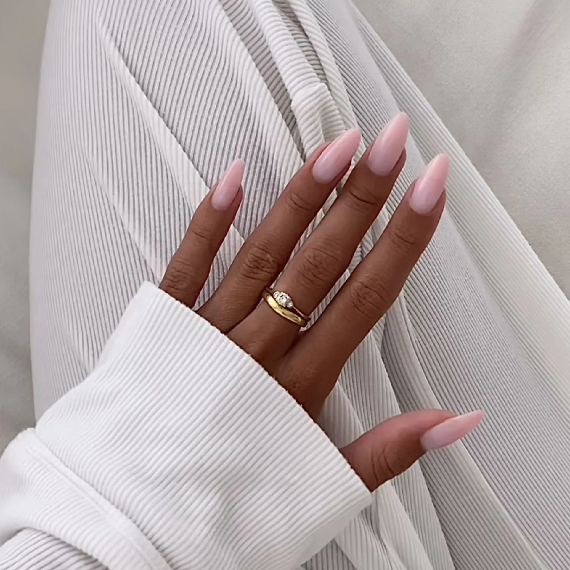 Close-up of long almond-shaped gel nail extensions in a soft pink finish