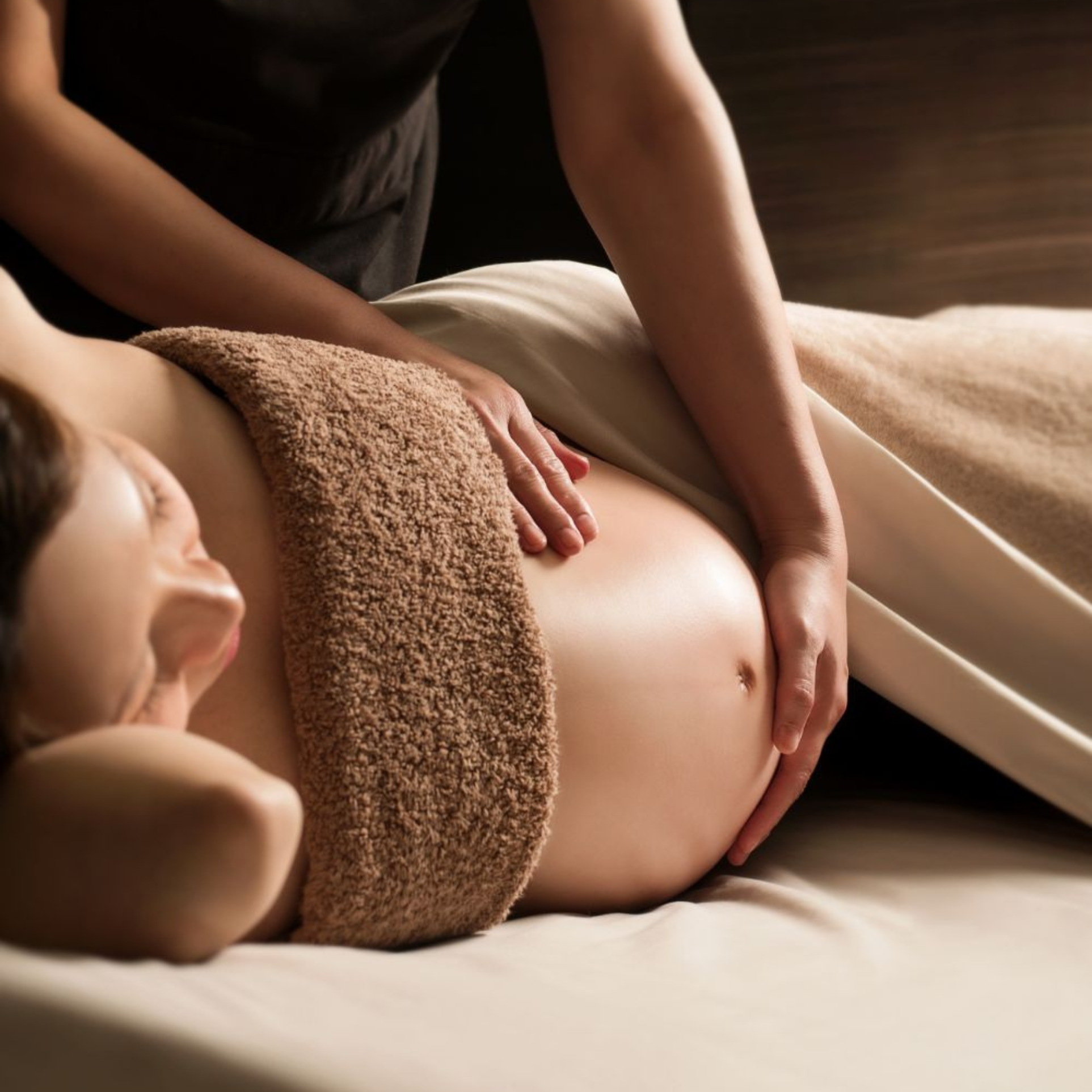 Therapist giving a pregnancy massage to a side-lying expectant client during an at-home treatment