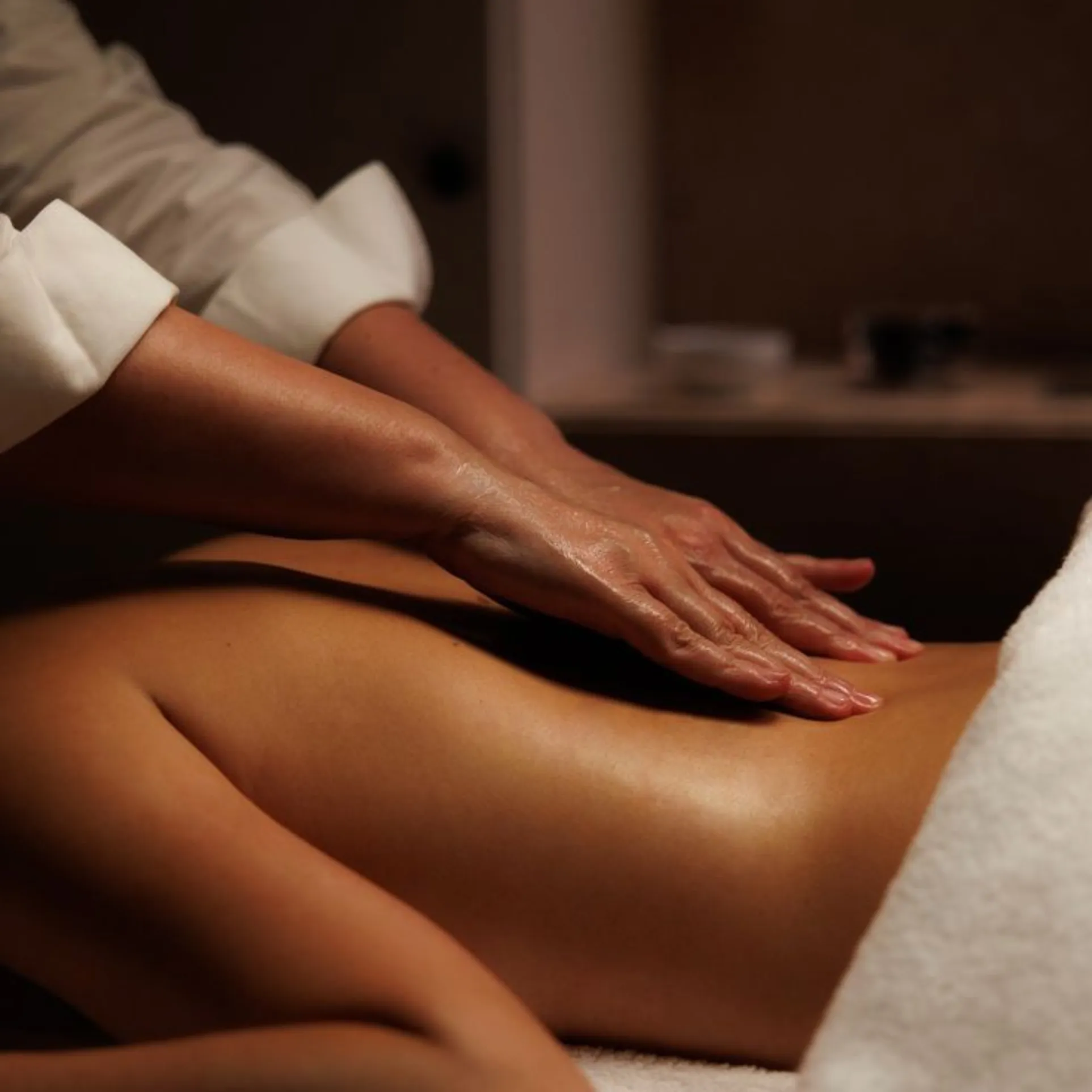 Therapist performing smooth, flowing strokes during a bespoke massage at an at-home treatment