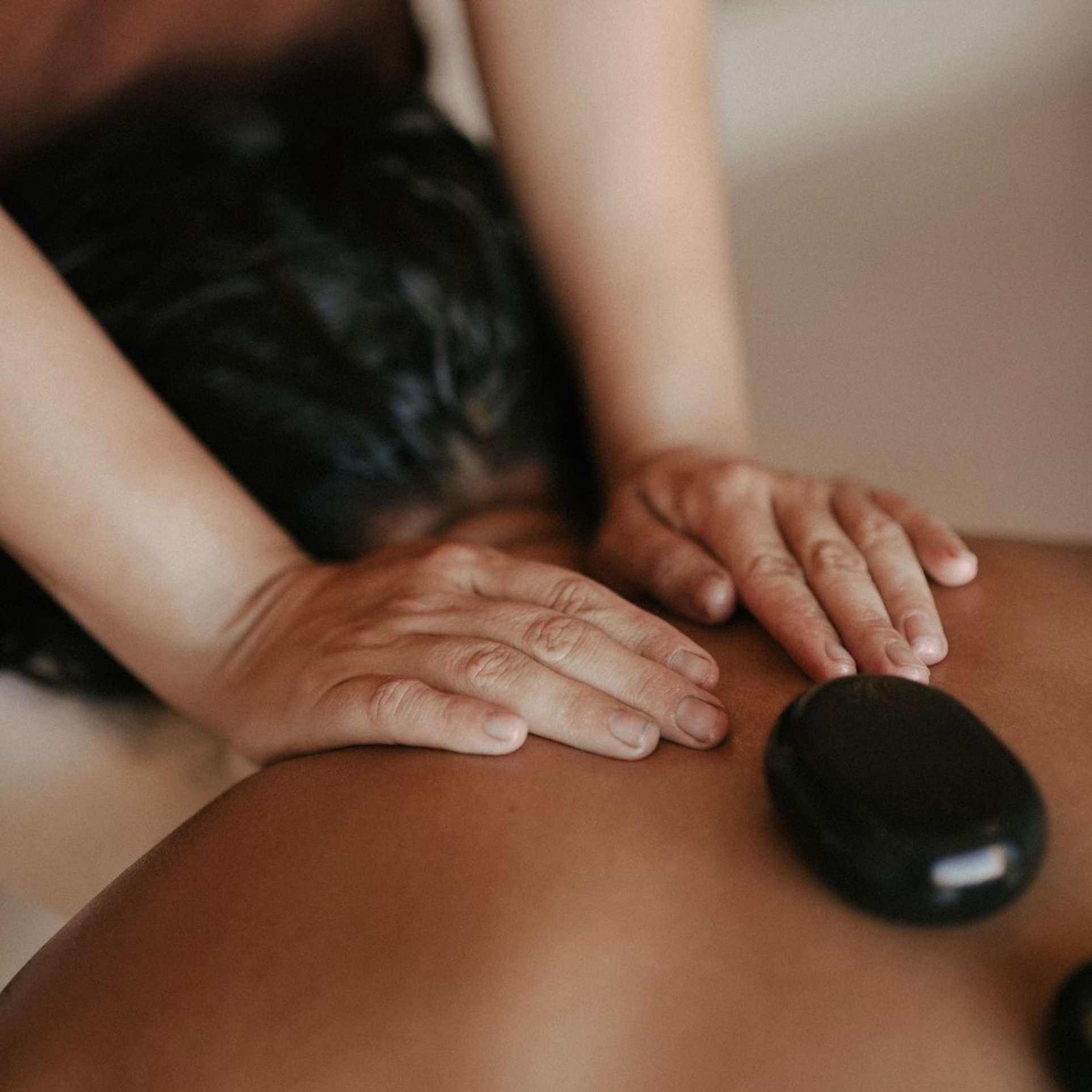 Therapist using a heated basalt stone during a hot stone massage at an at-home treatment