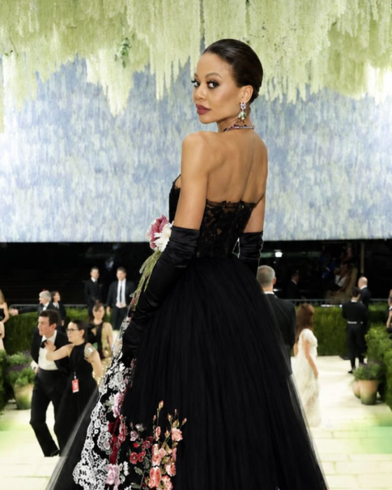 Emma Thynn, Marchioness of Bath, looking over her shoulder in a strapless black tulle gown with floral embroidery and long opera gloves, at a formal event.