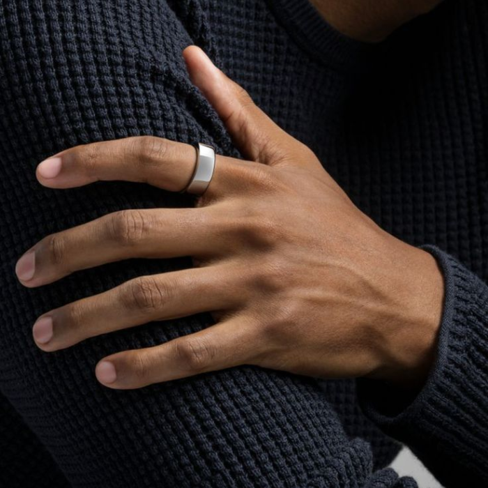 Close-up of a man's well-groomed hand resting on a navy knit, showing neat, buffed nails from a men's manicure.