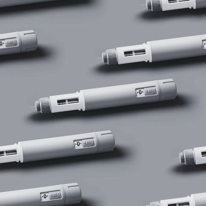 A repeating pattern of injectable pen devices arranged in rows against a grey background.