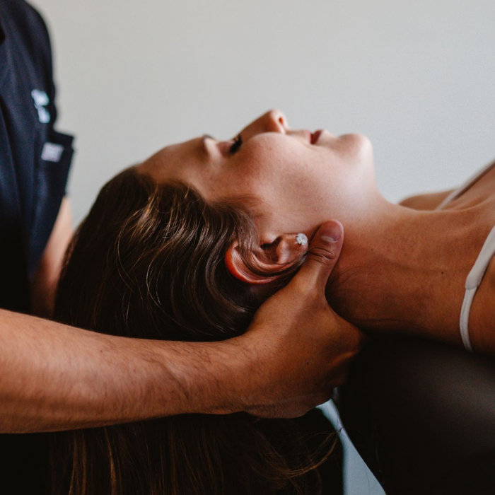 Clinician performing a neck mobilisation on a woman lying on a treatment table during a physiotherapy session.