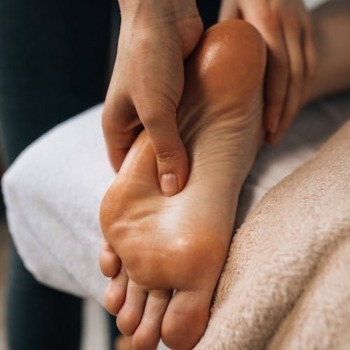 A therapist's hands applying pressure to the sole of a person's foot during a reflexology treatment.