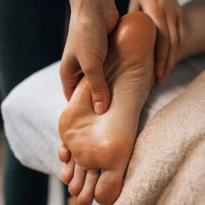 A therapist's hands applying pressure to the sole of a person's foot during a reflexology treatment.