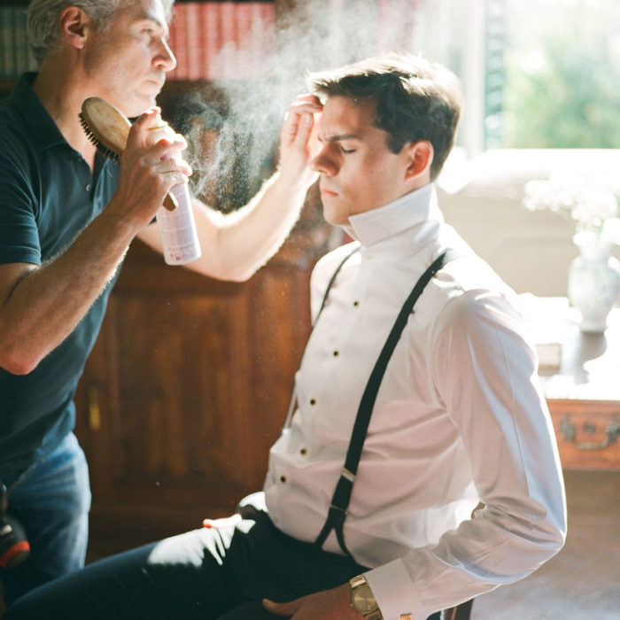 Groom having his hair styled by a grooming professional on the wedding morning