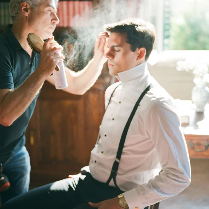 Groom having his hair styled by a grooming professional on the wedding morning