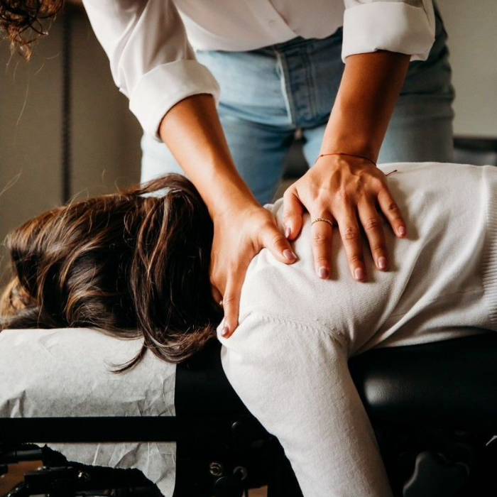 Osteopath performing a back and spine treatment on a woman lying face down on a treatment table