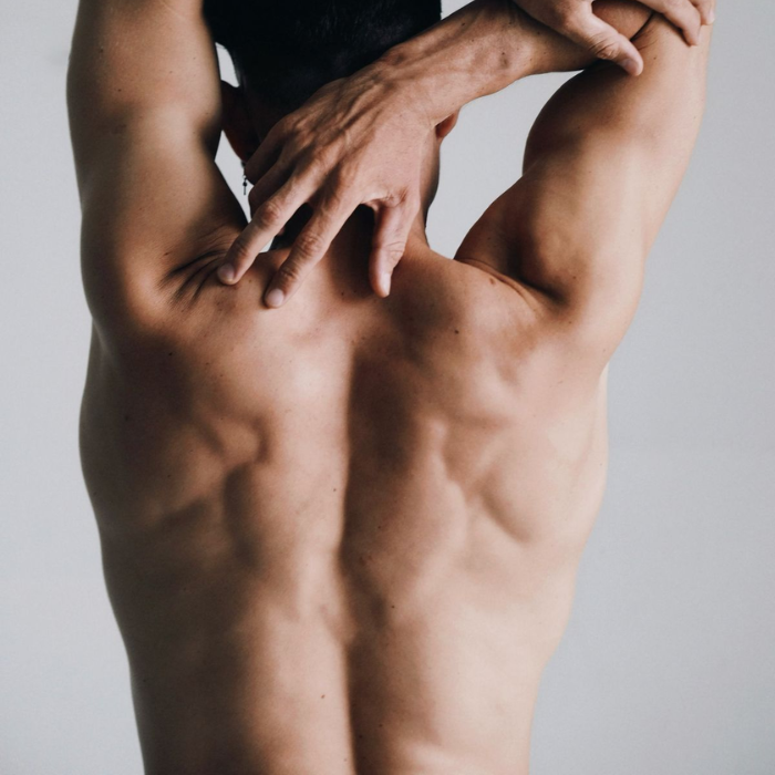 Man's smooth, hair-free back and shoulders shown from behind, illustrating the results of male back waxing.