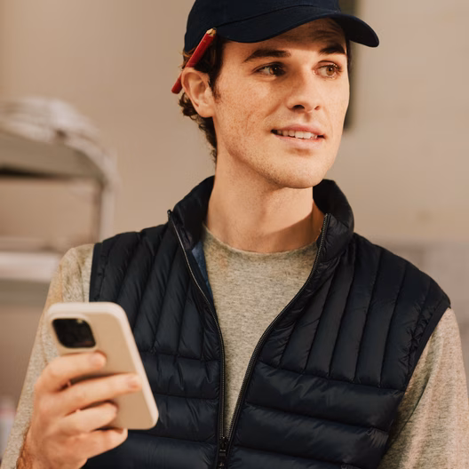 A tradesperson in a workshop checking their phone.