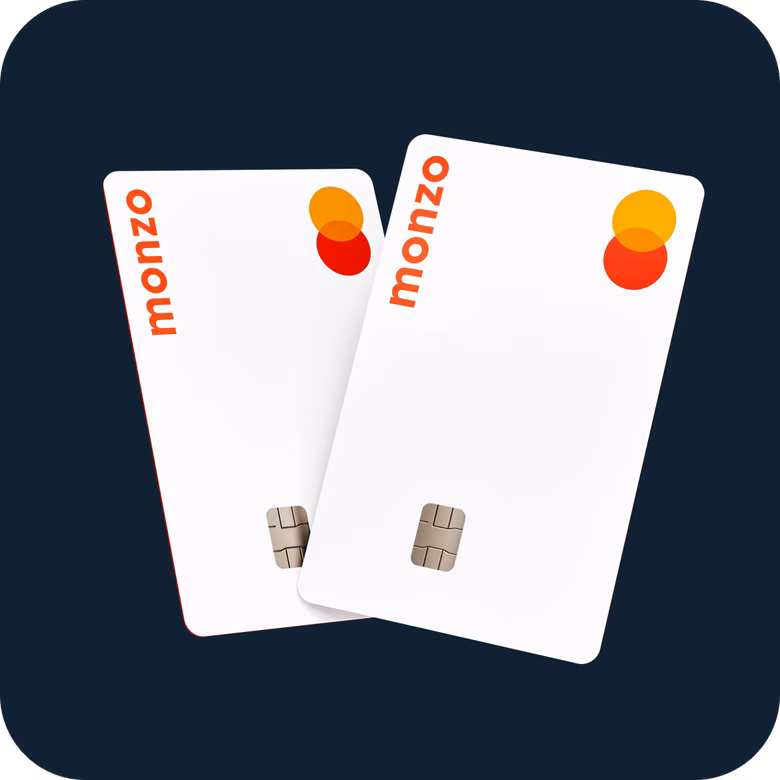 Ilustración de dos tarjetas bancarias blancas de Monzo colocadas una junto a otra sobre un fondo azul oscuro, ambas con un diseño de colores de Monzo.
