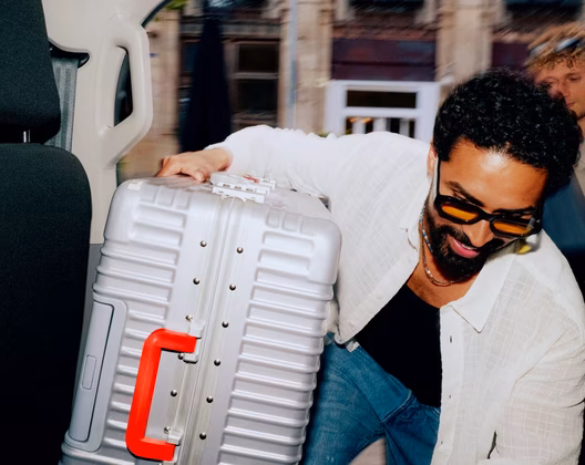 Man carrying a large suitcase into a taxi